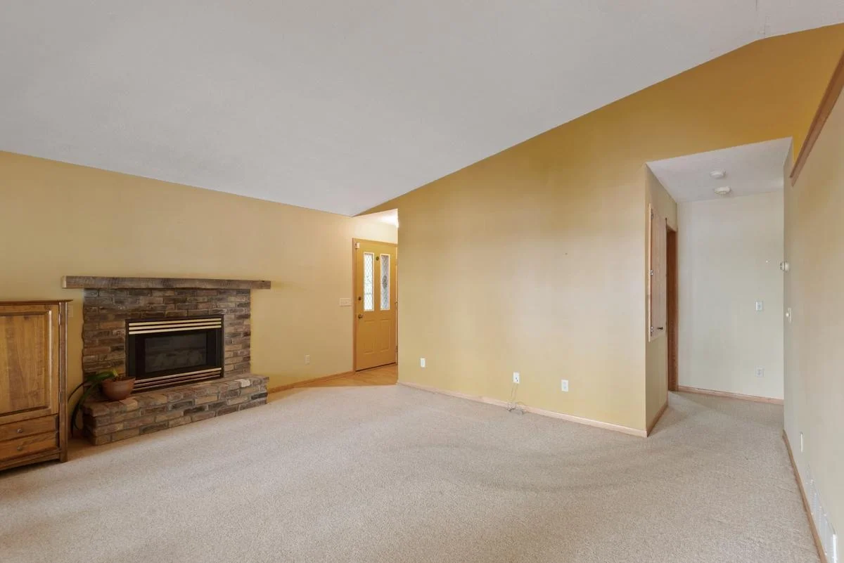 The inviting living room offers a cozy brick fireplace with a rustic wood mantel—an ideal place to gather on chilly evenings.