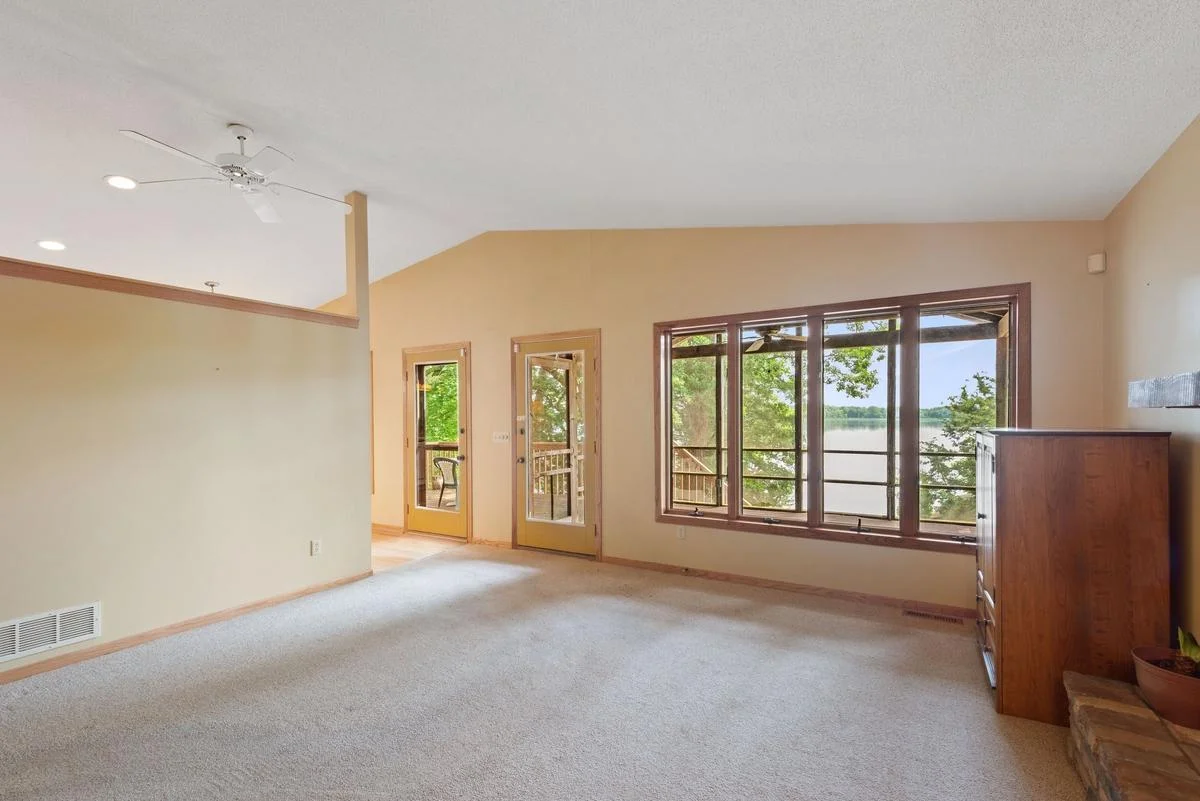 Enjoy scenic views of the screened porch and lake through the living room windows, with direct access from the living room to both the porch and lakeside deck.