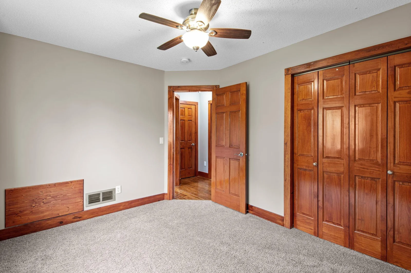 The second bedroom on the upper level includes a ceiling fan and gorgeous wooden doors.