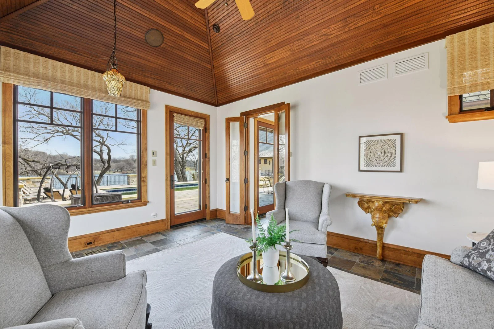 Wood paneled ceiling and walk-out access to the pool and lake beyond