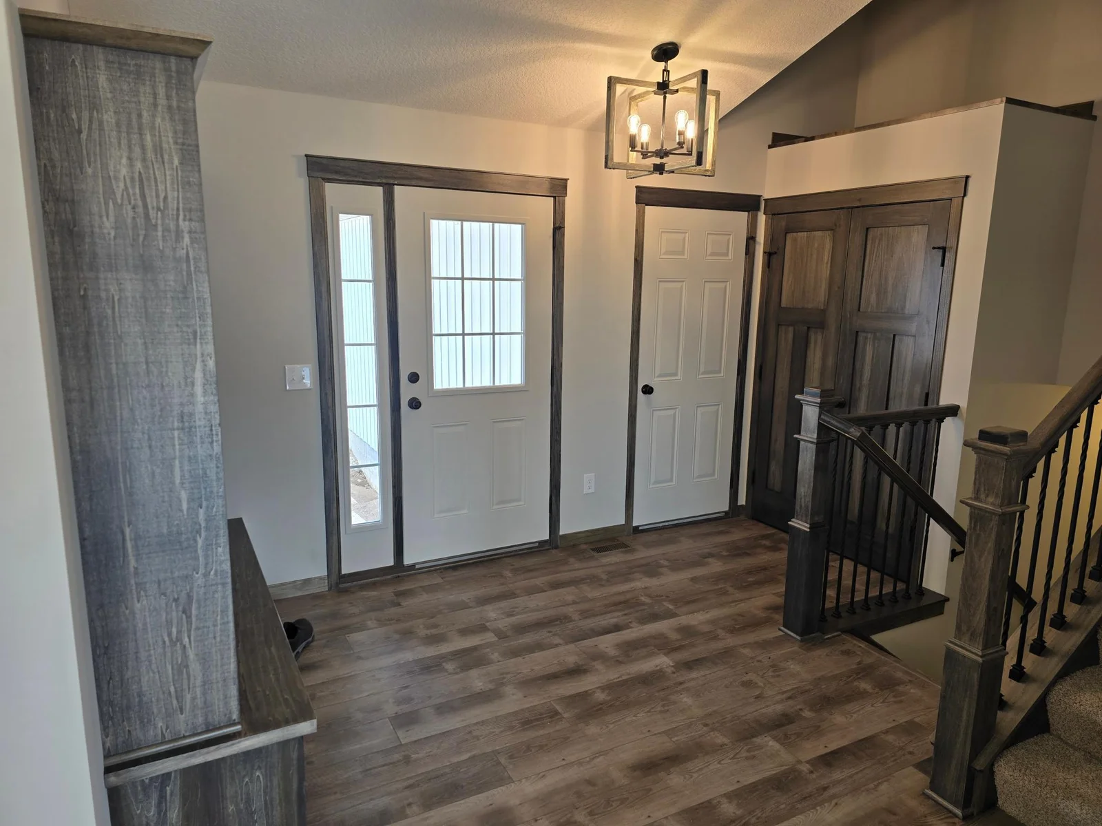 3 Paneled double swing doors on the entryway closet that is open above and has a wood cap.