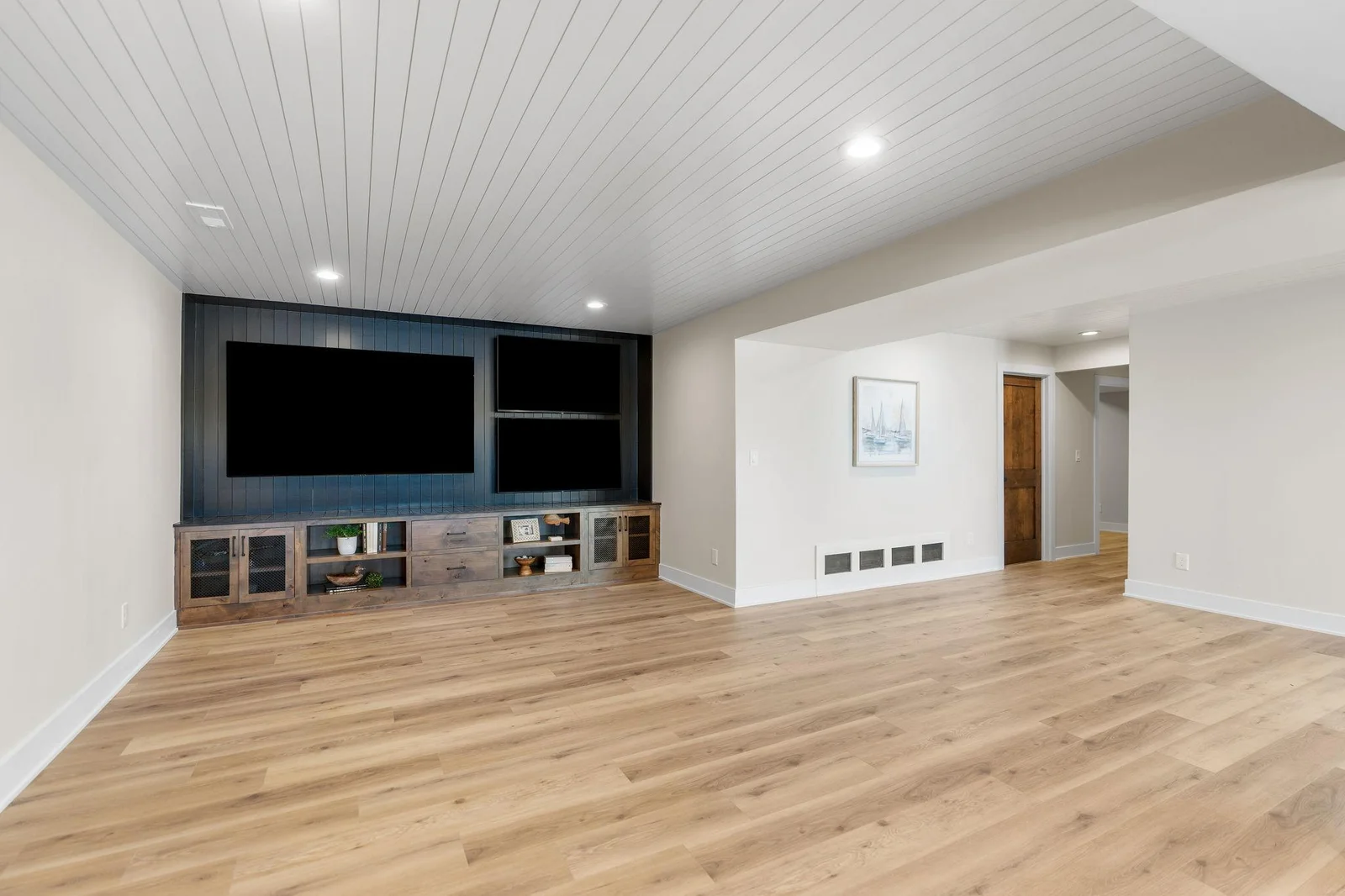 Rustic alder entertainment center offers storage, open display shelving, enameled wood paneled accent wall with 3 TV's!