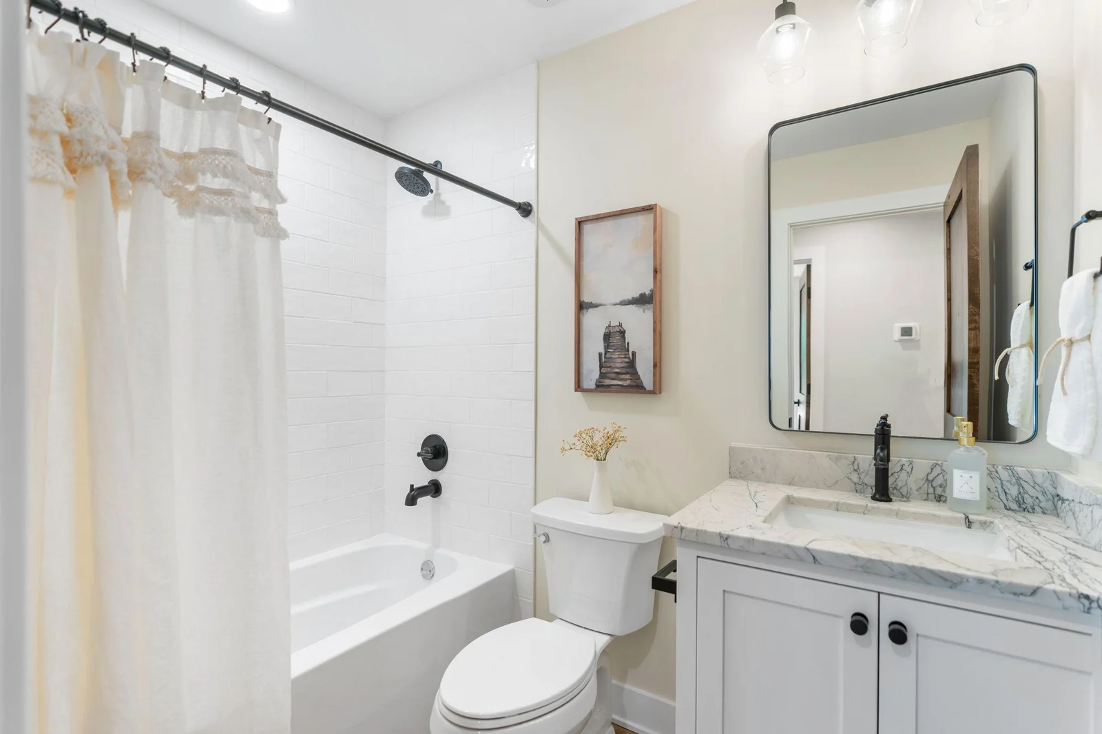 Full bathroom on the main level features enameled vanity cabinet and natural quartzite top