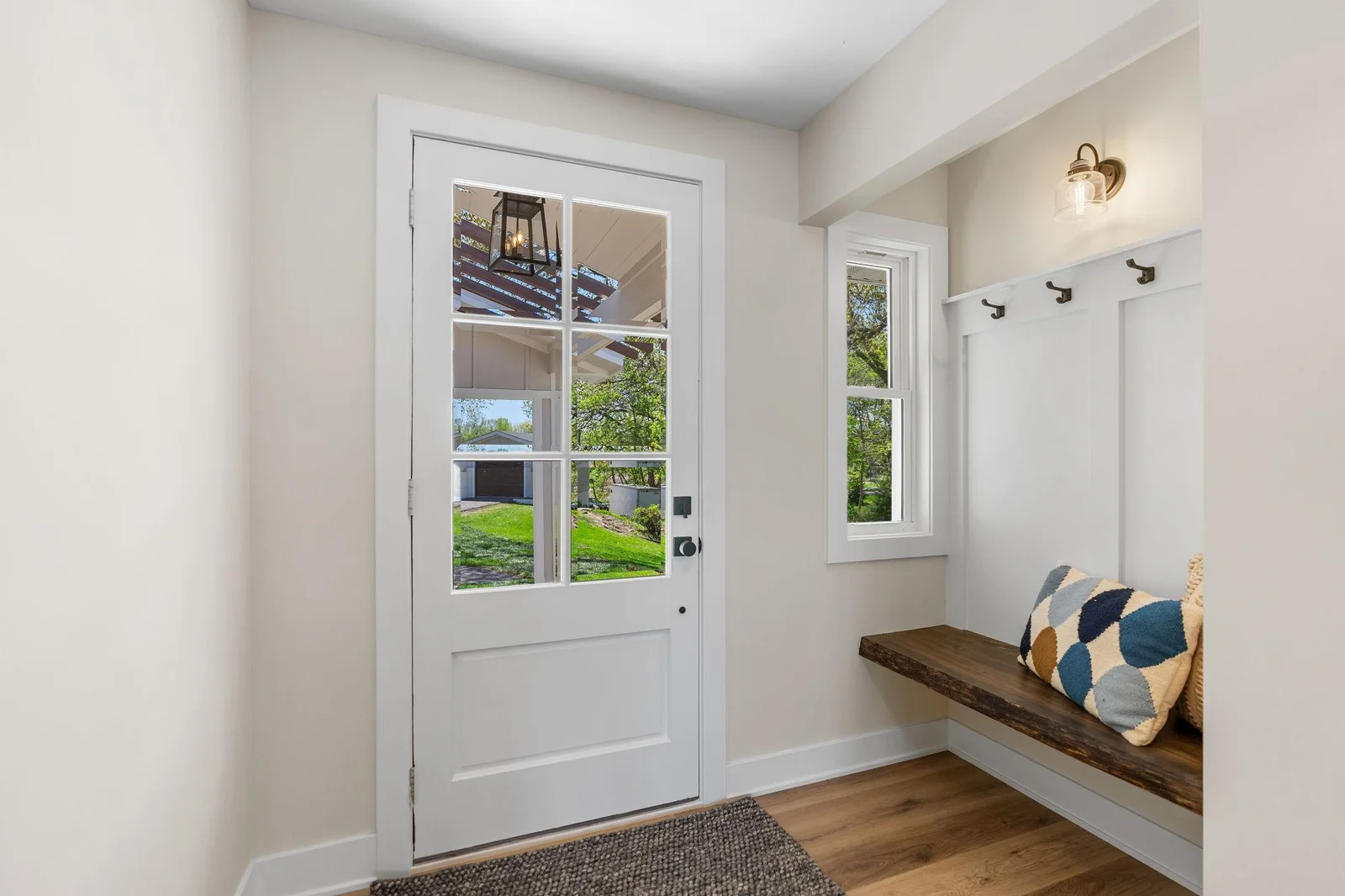Entry features a niche that offers a live edge bench, paneled accent wall w/ hooks and sconce