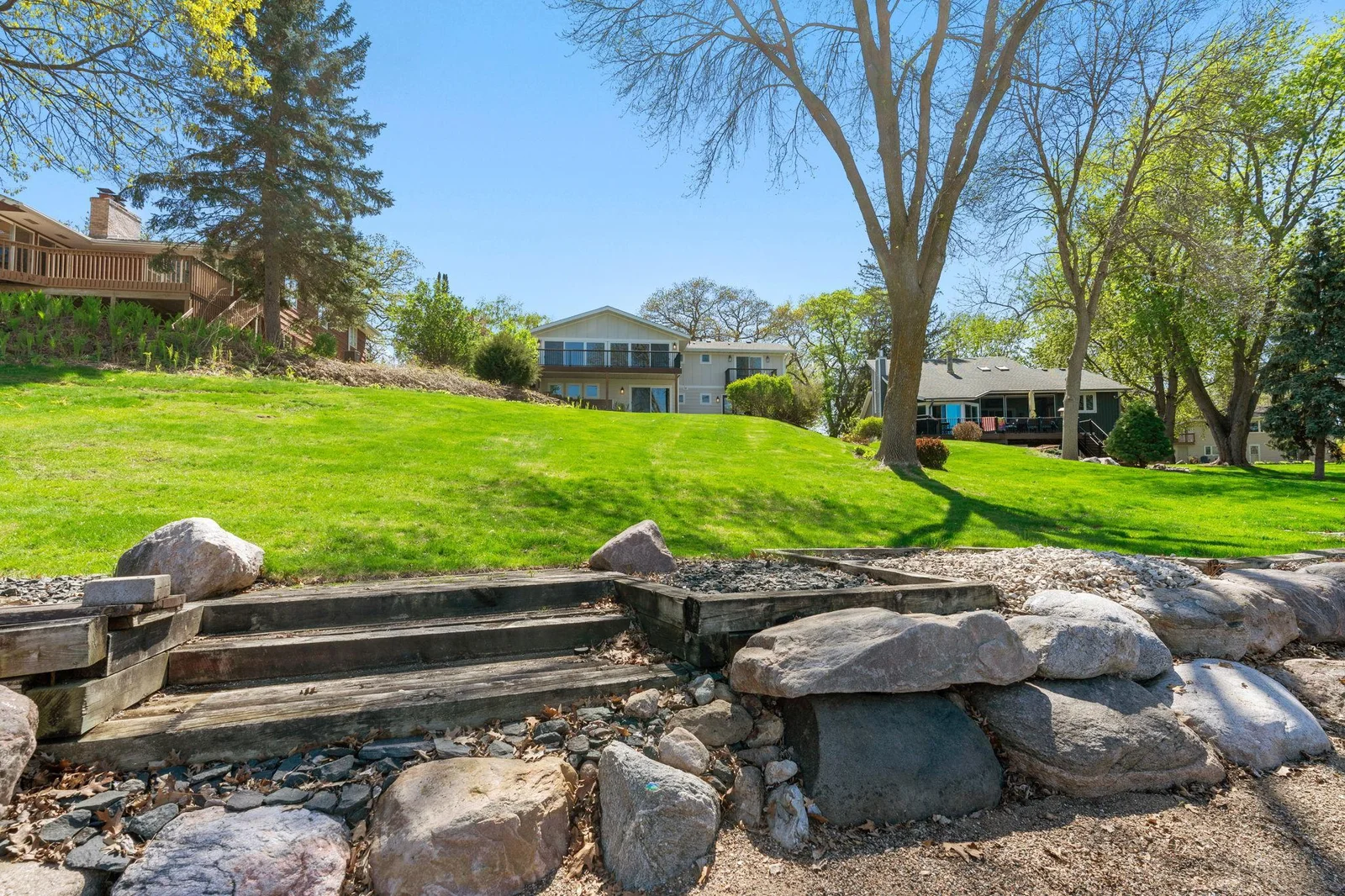 Property offers majestic trees, mature landscape and gardens, boulder retaining walls and expansive green space with gradual sloping to the lake