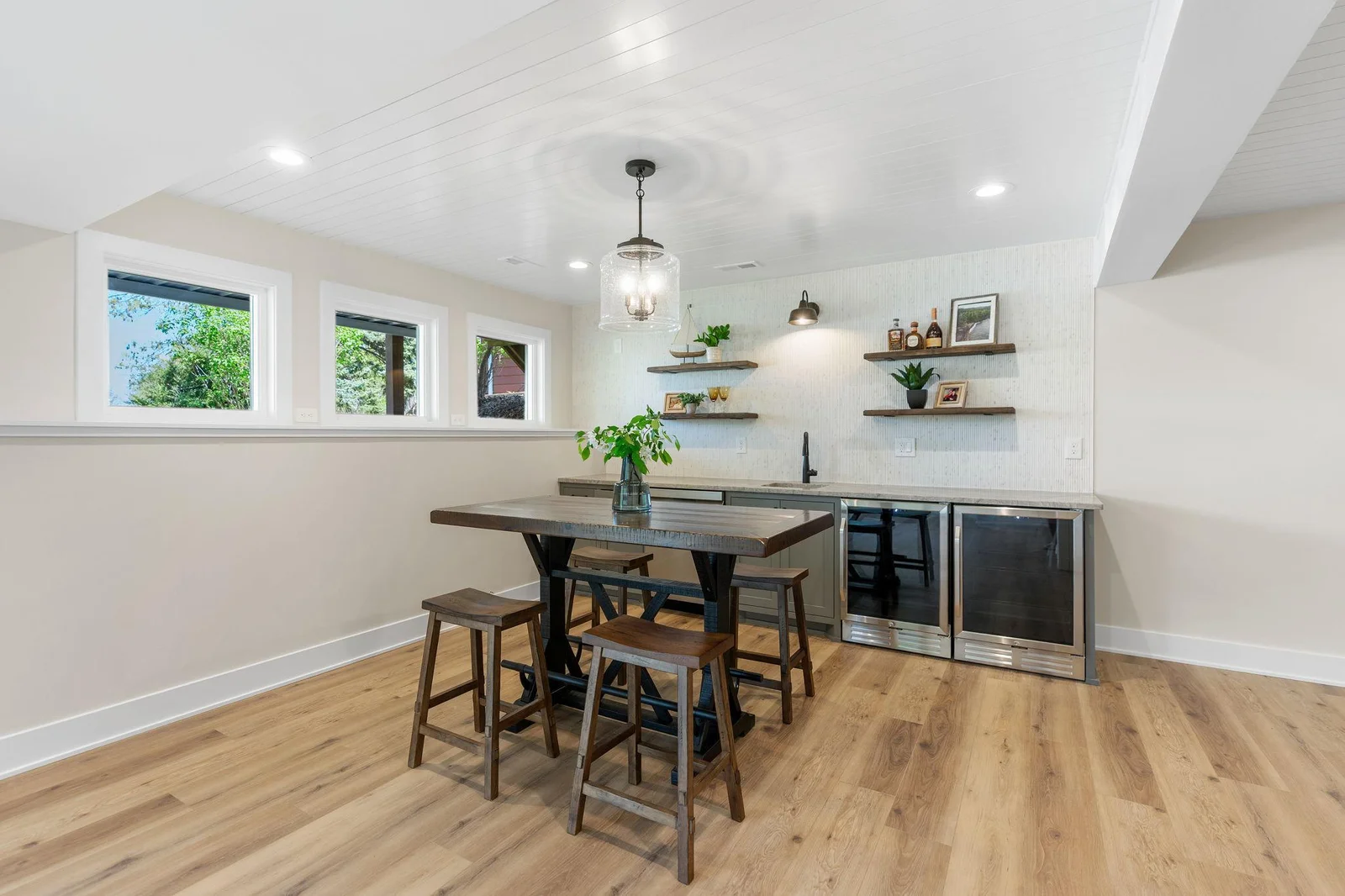 Built-in wet bar features enameled cabinetry, pair of beverage refrigerators, dishwasher, natural quartzite countertop and glass tile backsplash