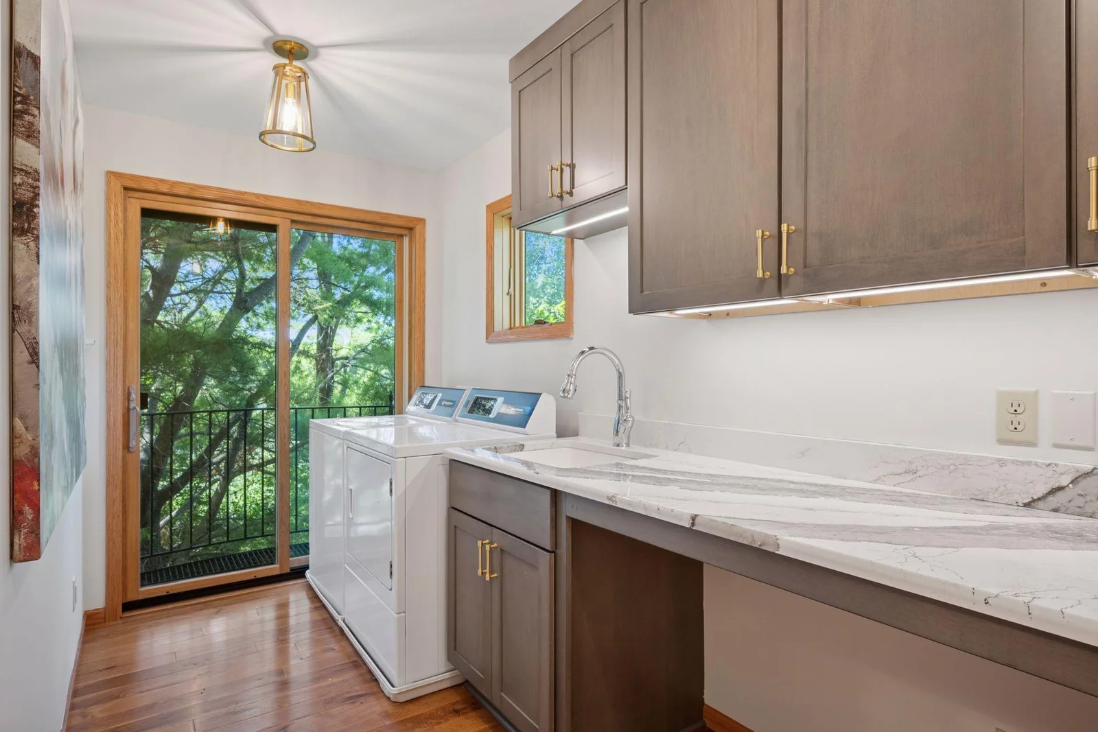 Upper level laundry room with custom cabinets, quartz countertops that double as a folding table and a sliding glass door make the chore a little more cheerful!