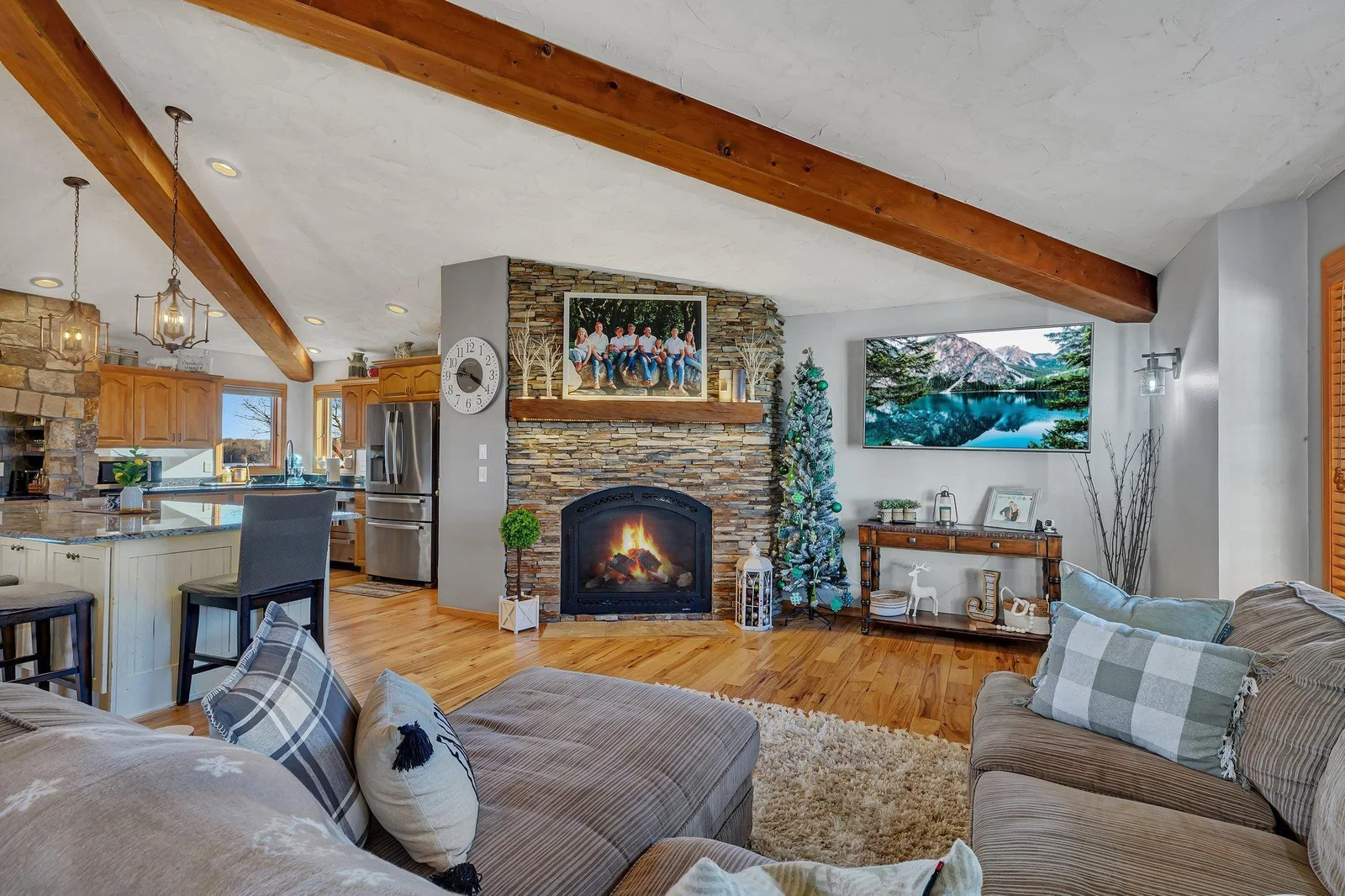Living room is accented by a floor to ceiling bricked fireplace.  Rustic beams merge this great room.