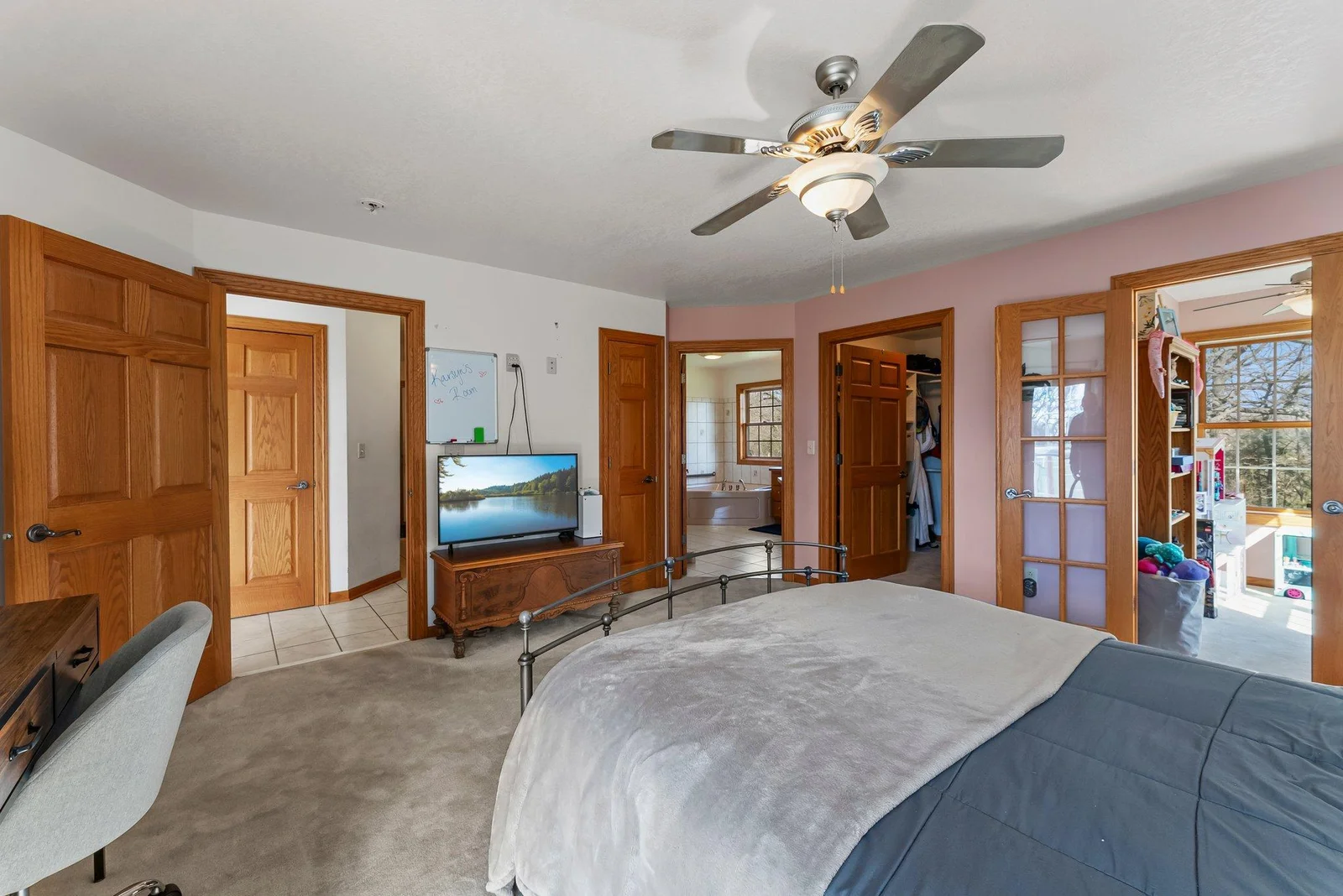 Main level First Primary Bedroom (aka, master bedroom). This view shows beautiful glass doors leading to walk-in closet and full private bathroom (ensuite).