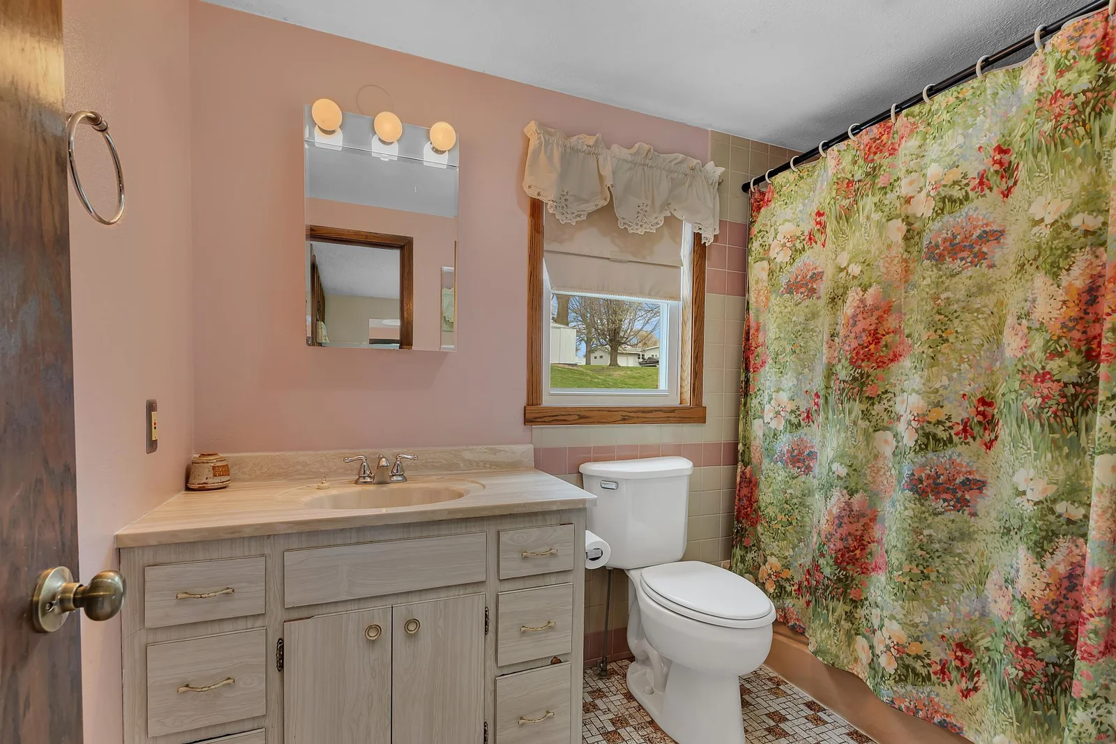 Main level full bathroom with tile flooring and a built-in linen cabinet.