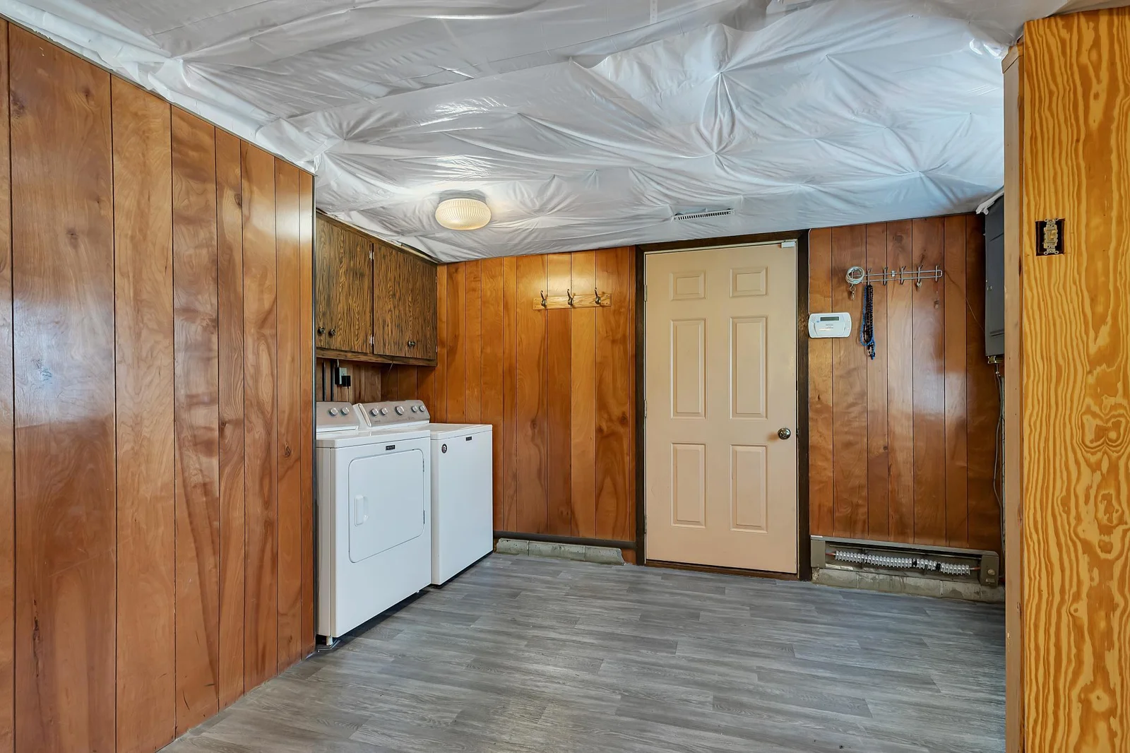 Lower level entry door and laundry room with a washer and dryer (new in 2020) and overhead cabinetry for storing laundry supplies. tuck-under garage is stubbed with a natural gas line—ready for your future heated workshop or cozy winter mornings.