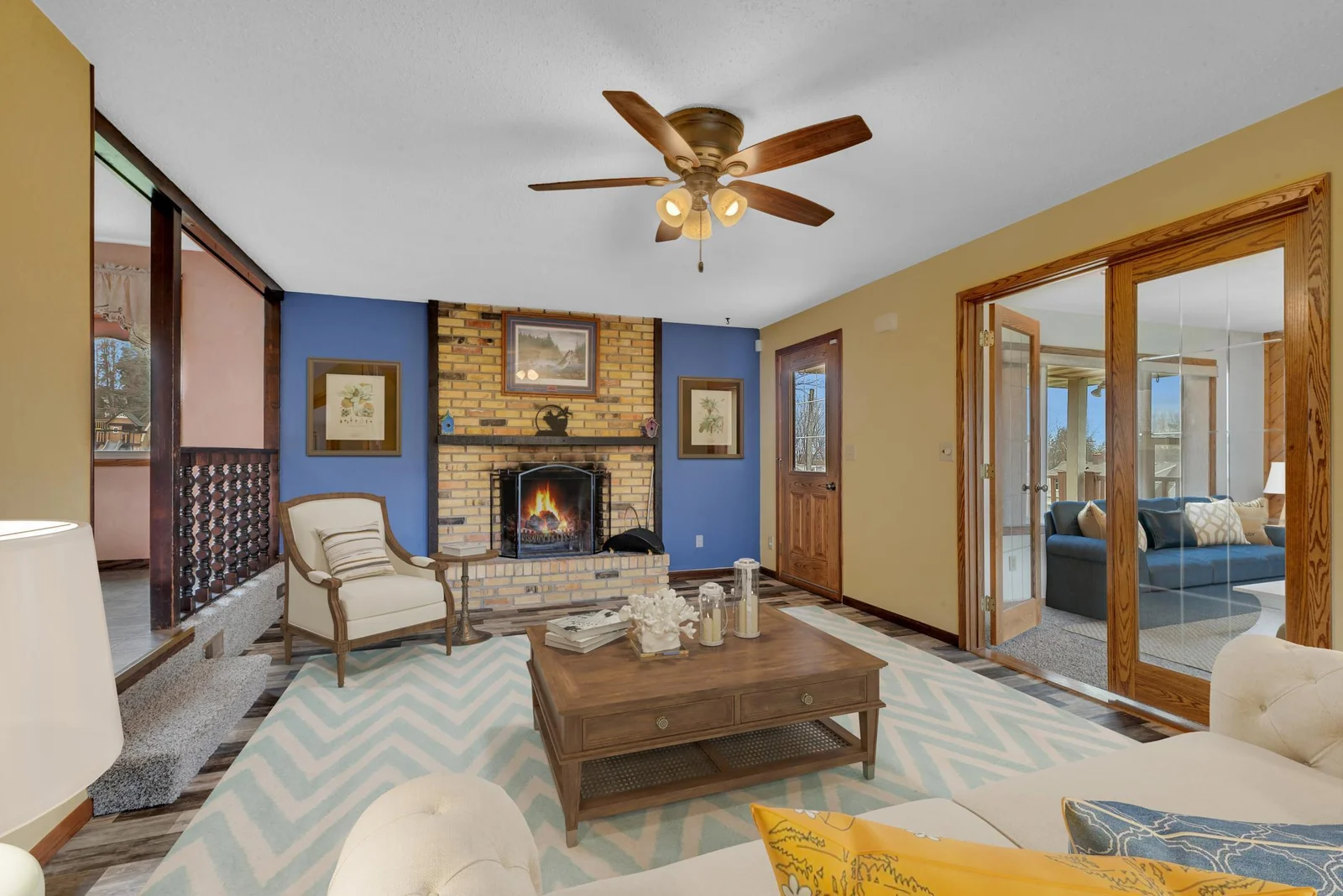 The living room features a wood burning fireplace and a ceiling fan to help disperse heat.