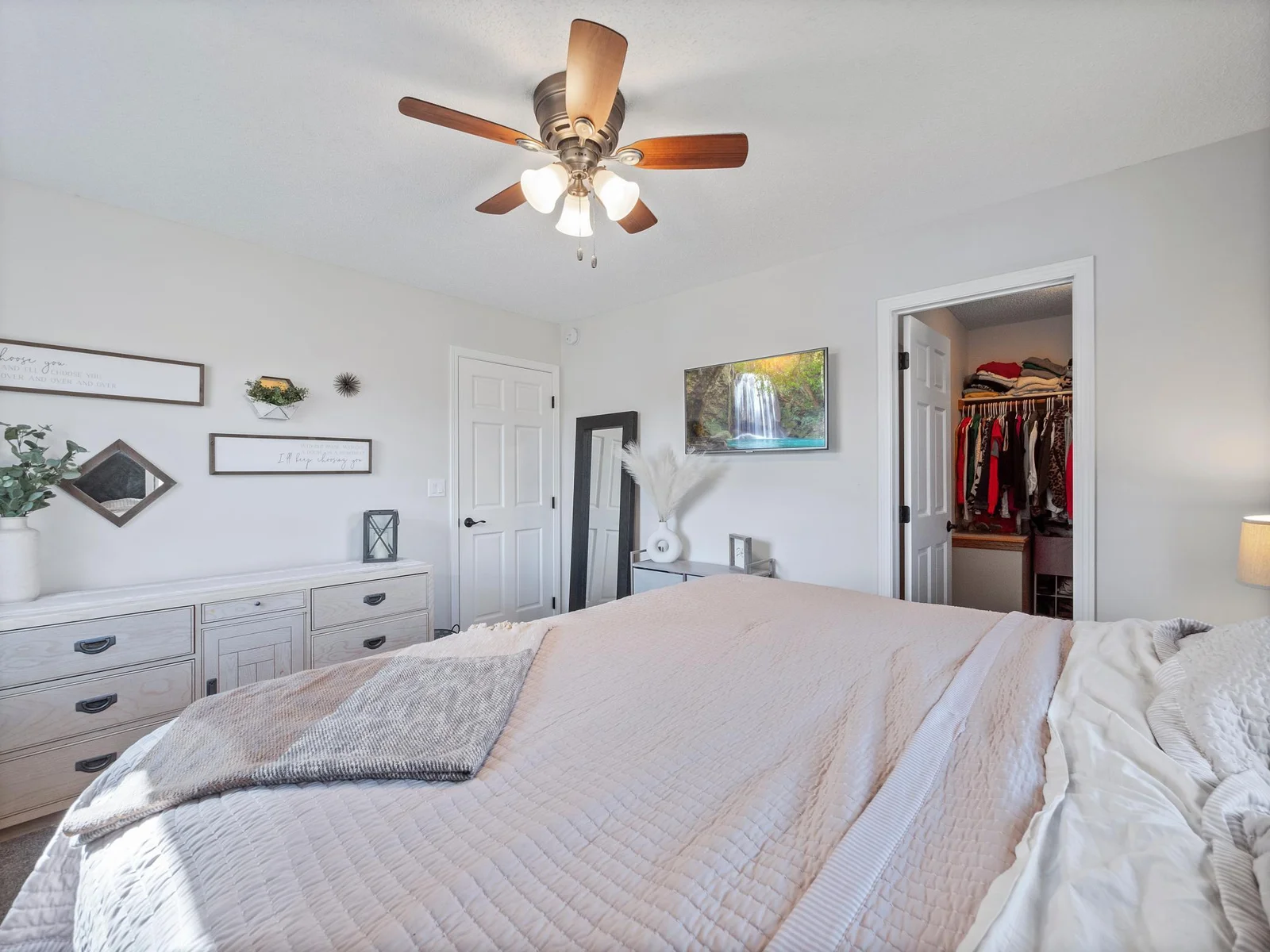 The primary bedroom oasis features neutral tones, plush carpet, and a ceiling fan for added comfort. The primary bedroom also has a walk-in closet and convenient access to the full shared bathroom.