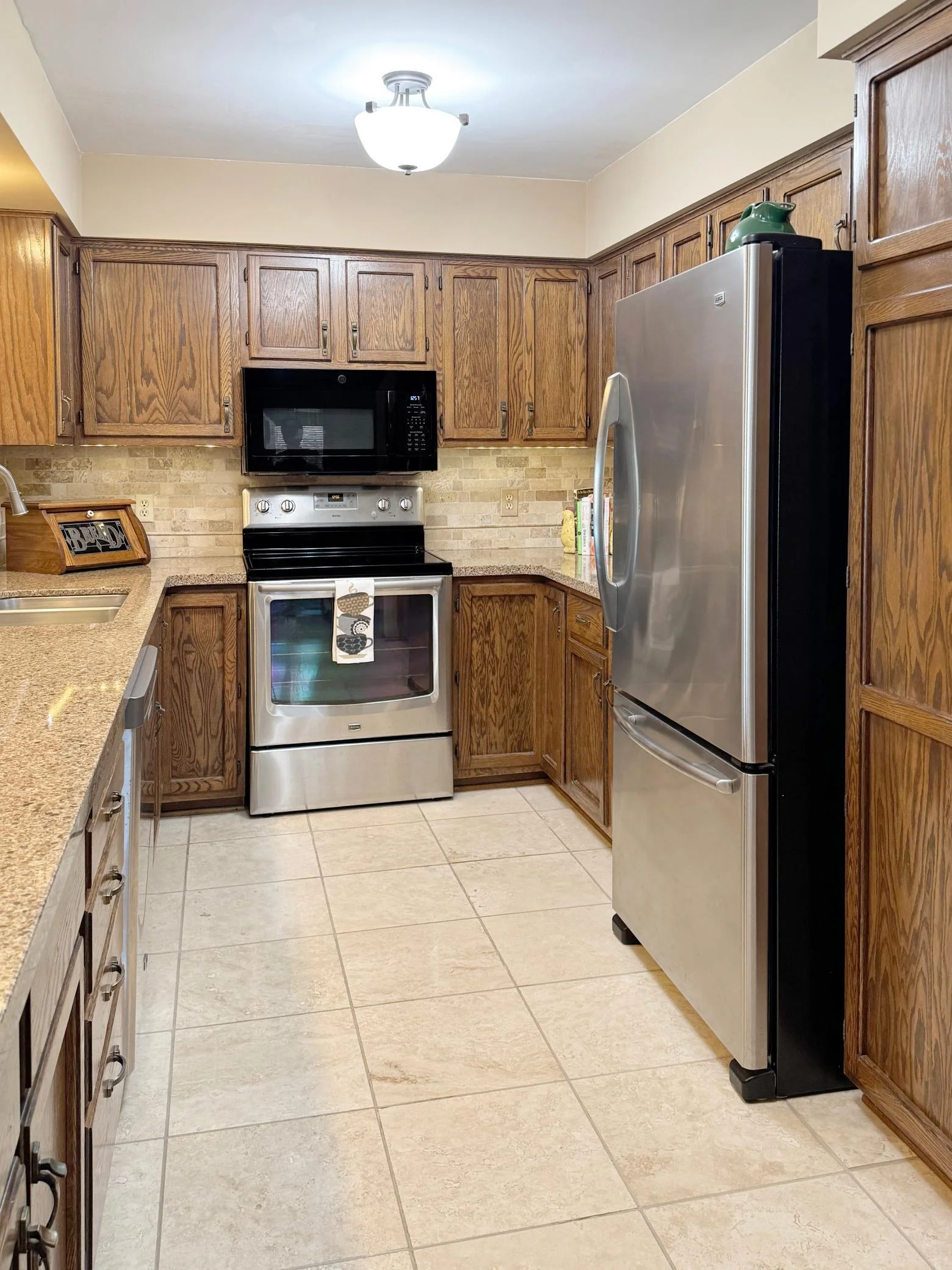Highly workable galley kitchen features quartz counters with backsplash and stainless appliances.,