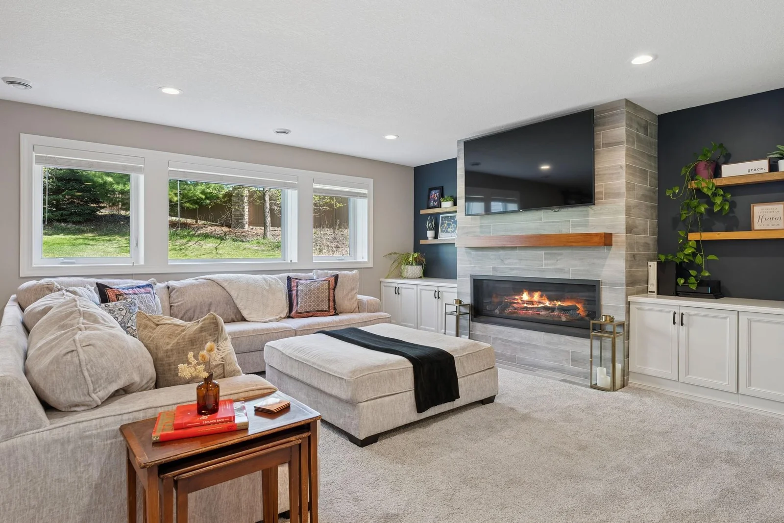 The TV area of the rec room features a tile-surround fireplace, built-in cabinetry & shelving and extra plush carpeting. The large windows and recessed lighting keeps the space very bright too!