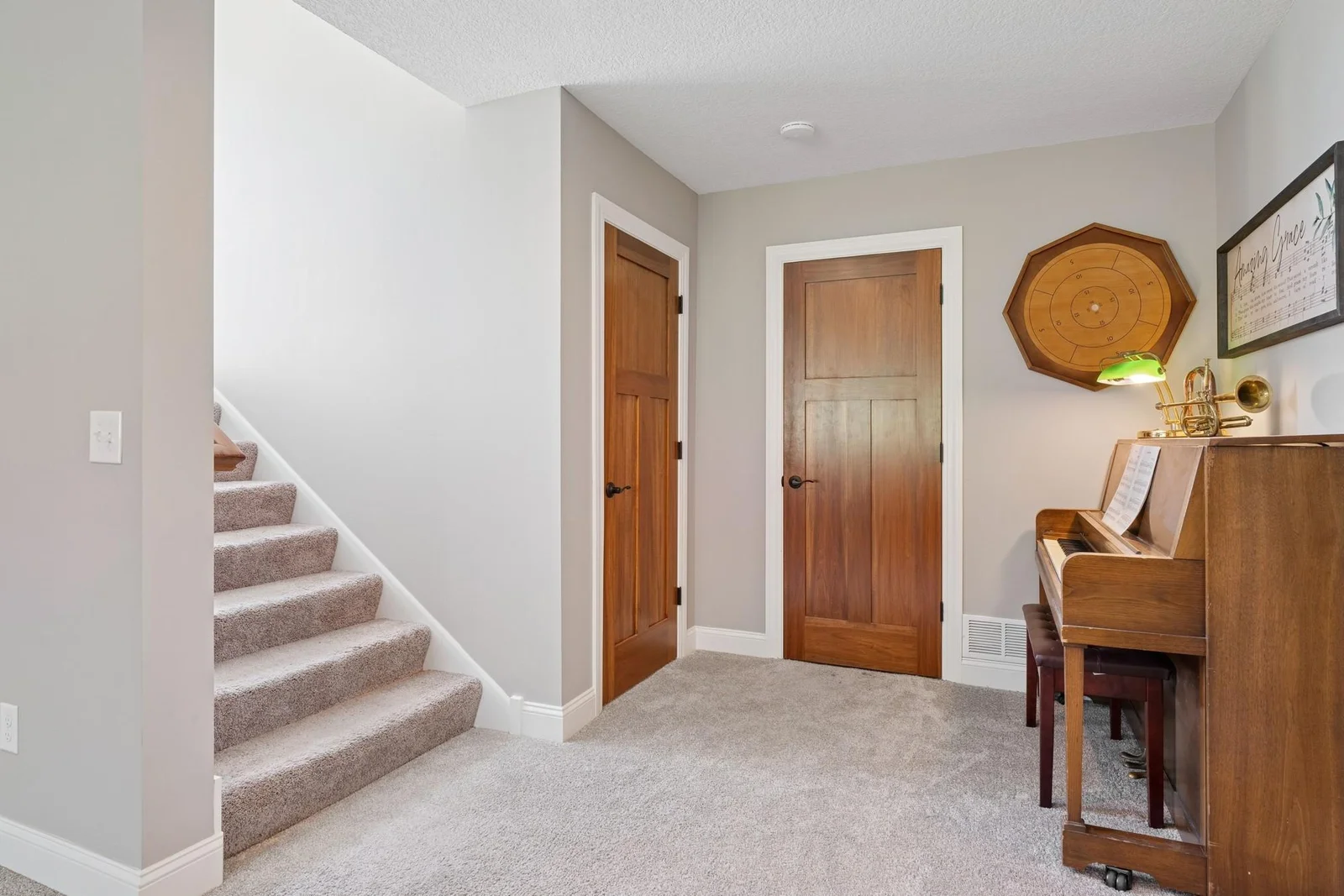 When you get to the lower level, the landing is large and open. The door on the left goes to the under-stairs storage closet and the other one goes to the utility & storage room.