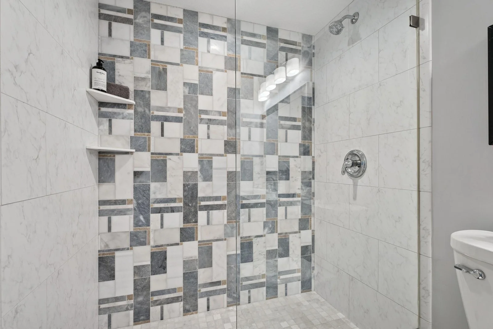 The tiled shower is tiled all the way up to the ceiling, and tile flooring too, and also features a custom, frameless glass partition.