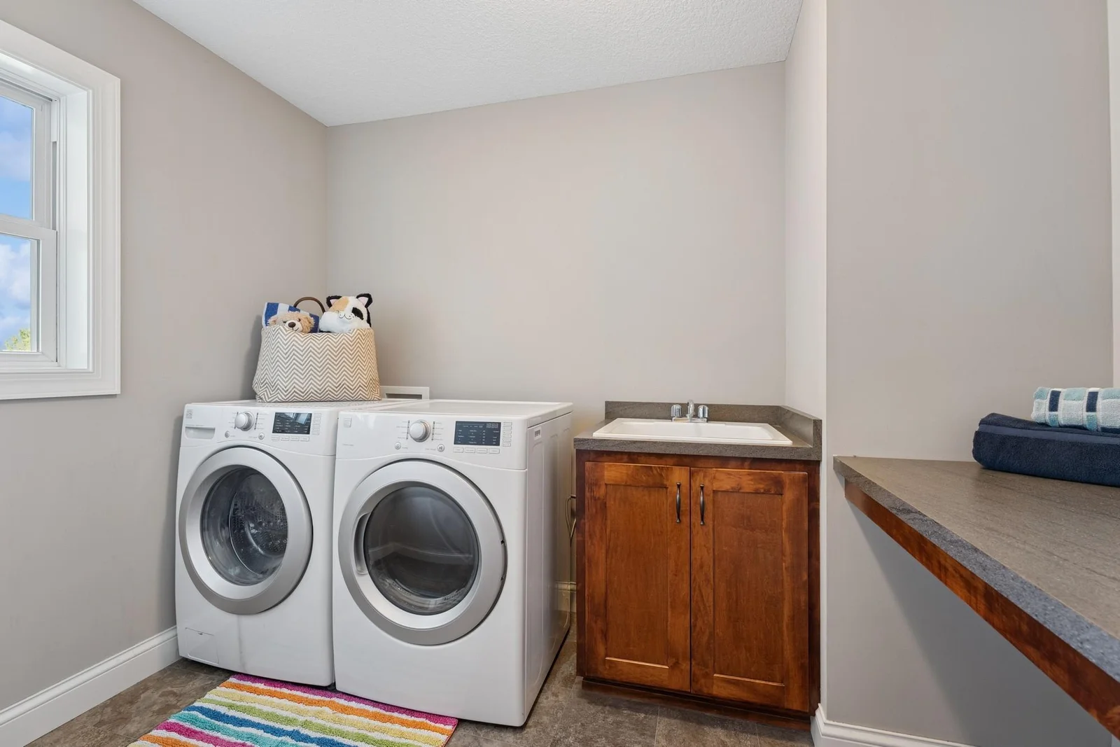 The laundry room is equipped with high-efficiency, front loading machines, a drop in sink & cabinet and a built-in folding table.
