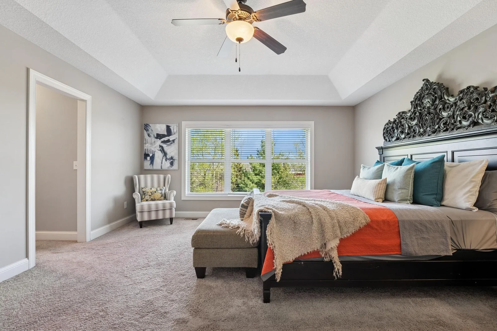 The primary bedroom features a ceiling fan, a tray vault ceiling, and huge east facing windows, to help you wake up in the morning.