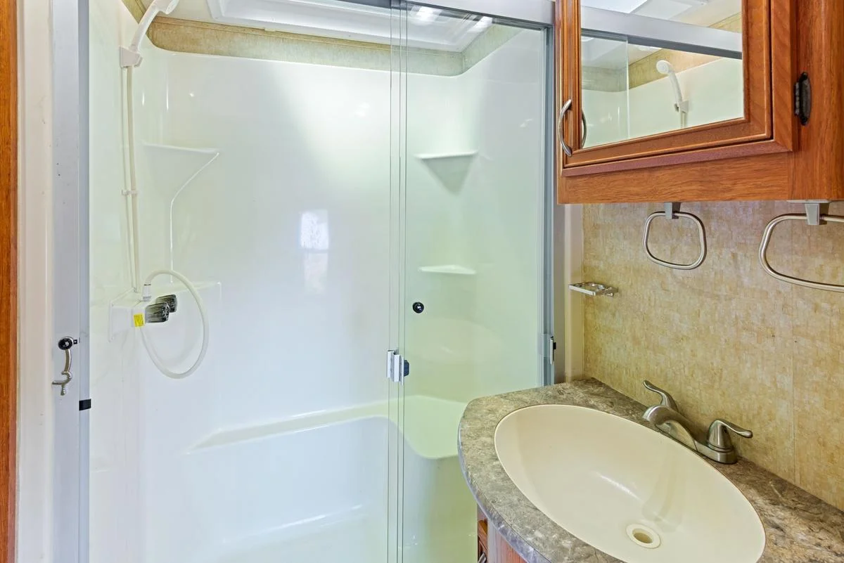 A skylight above the shower brings in natural light, while the vanity and mirrored medicine cabinet offer ample room for storage.