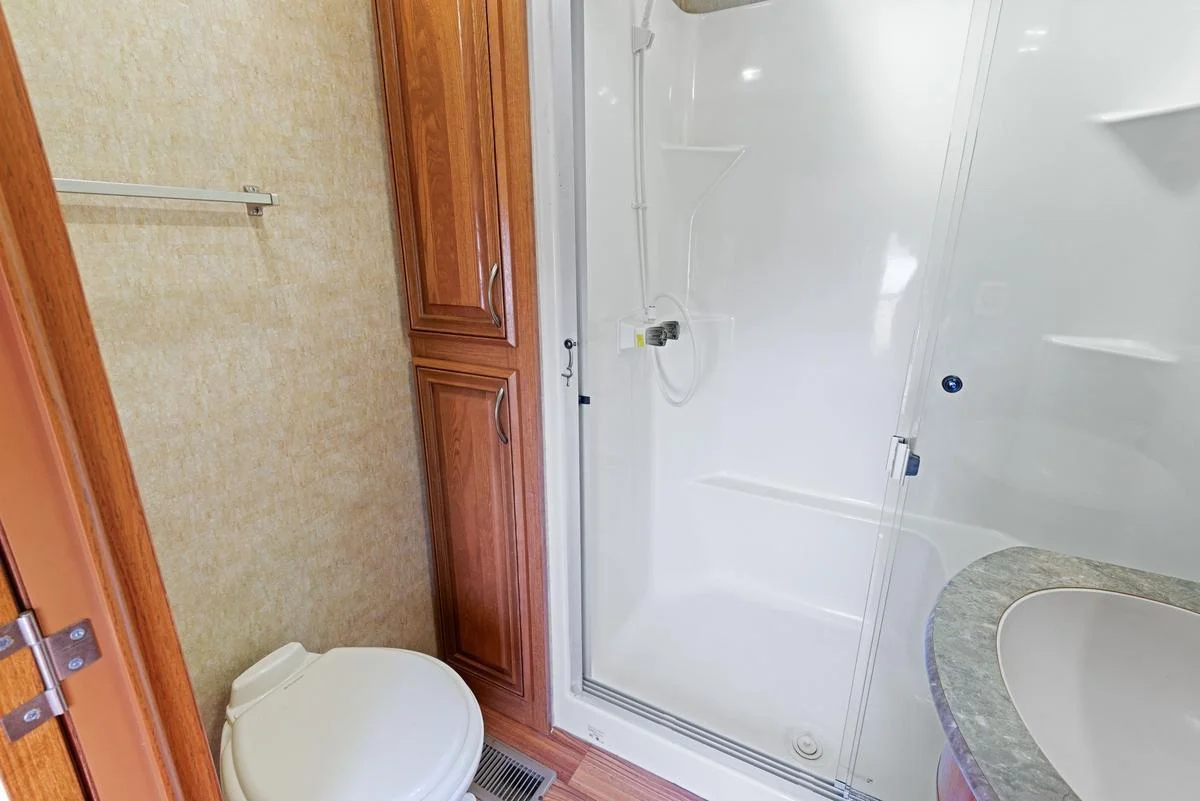 This well-appointed ¾ bathroom maximizes space and functionality with a spacious shower featuring sliding doors, seating and built-in shelving.