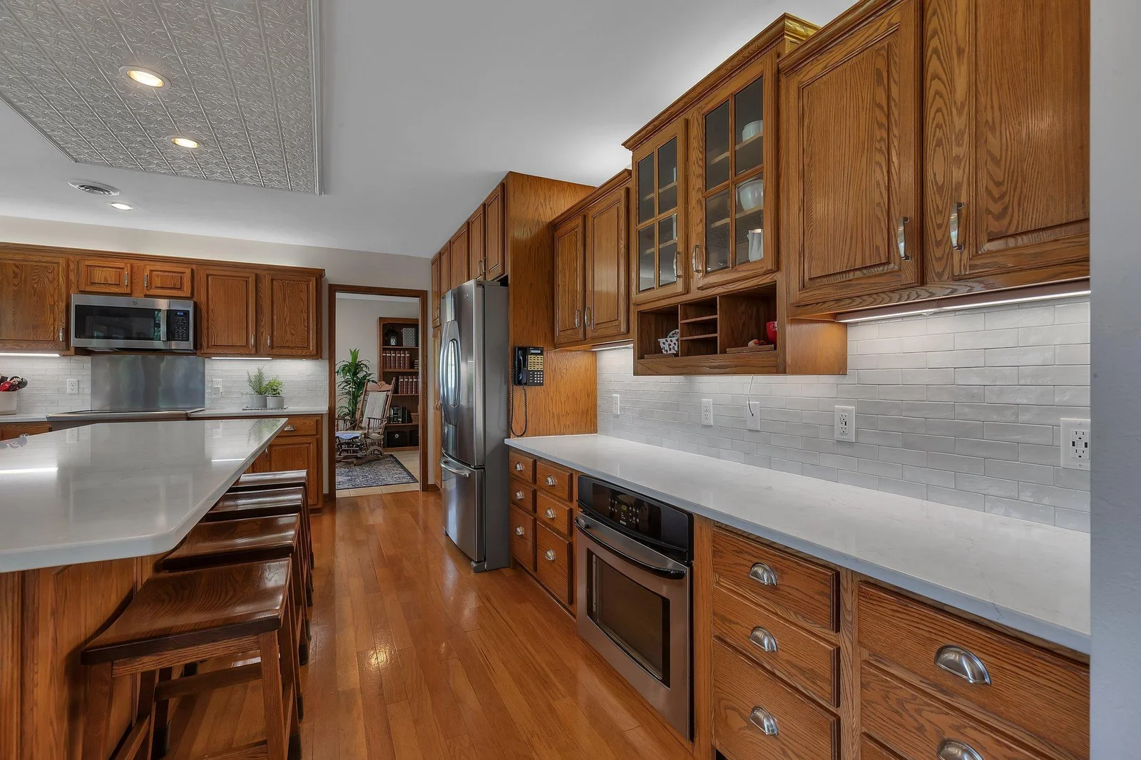 Quartz-topped island, ceramic backsplash, and glass front display cupboard.