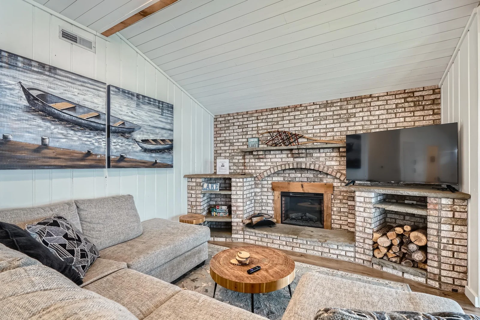 Living area offers a warm, inviting atmosphere designed for relaxation with a statement brick fireplace and built-in shelving.