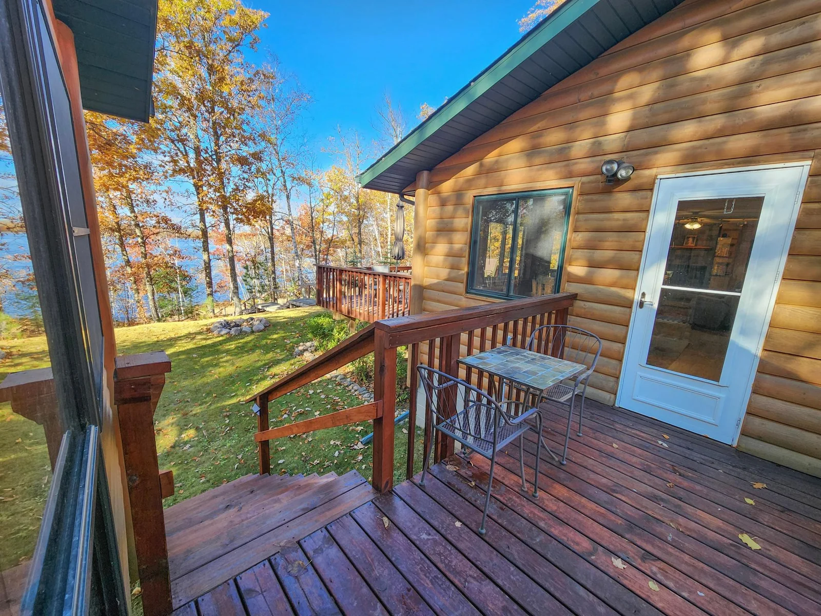 Deck between porch and cabin, stairs one way to the front yard and lake, stair the other way to parking and back of home.