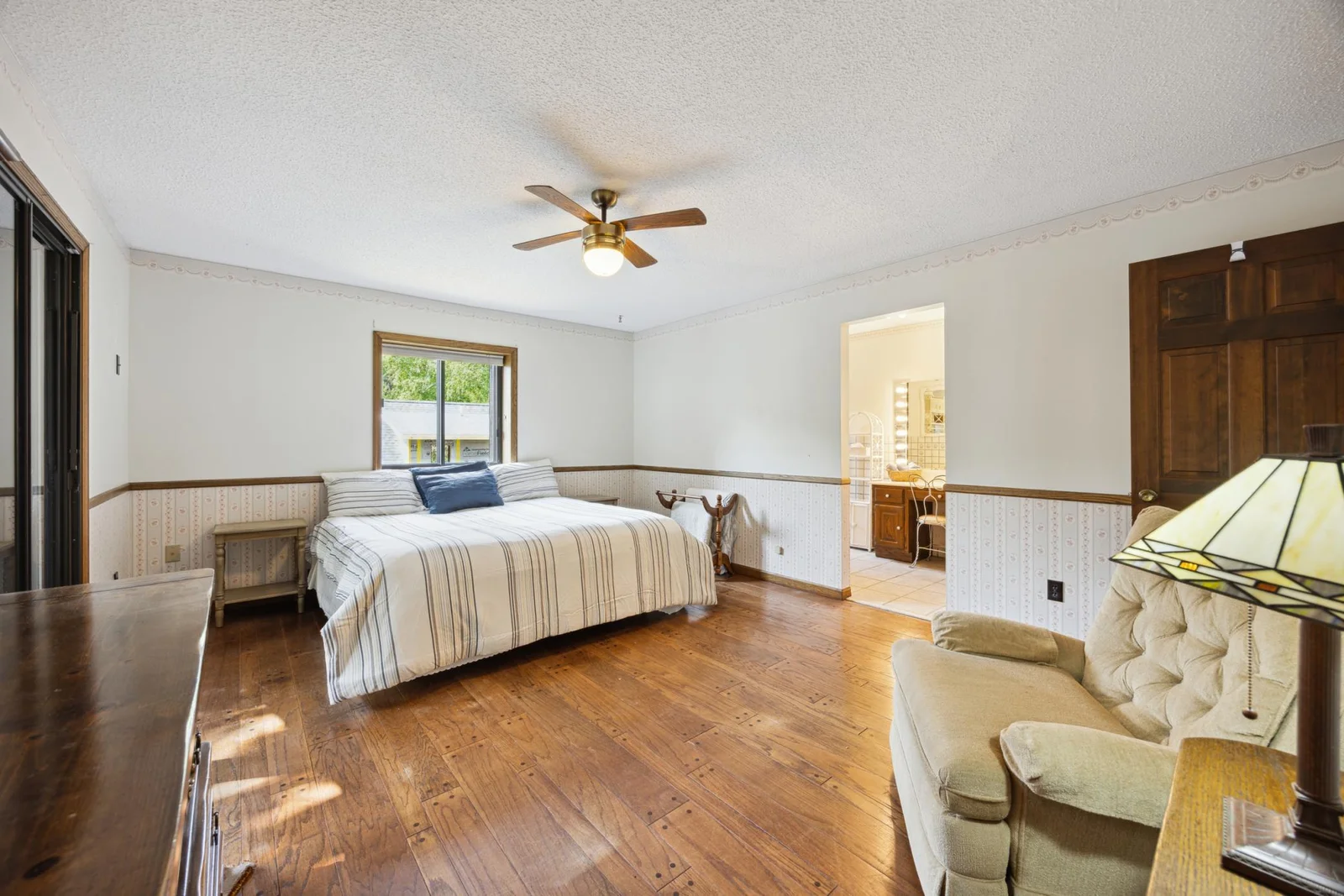 4 bedrooms on the upper level.  This is the primary bedroom with bathroom and walk-in closet. On the left there is a patio door to a balcony overlooking the lake.
