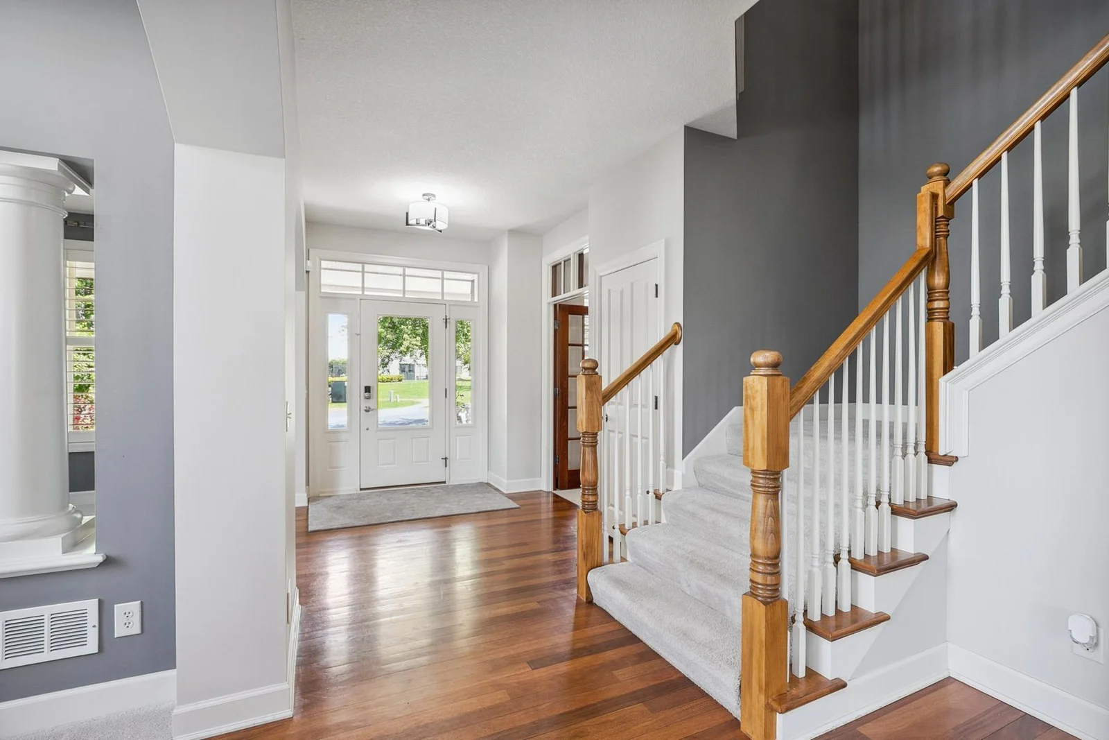 Step into a bright, beautiful foyer featuring rich cherry wood floors and timeless elegance.