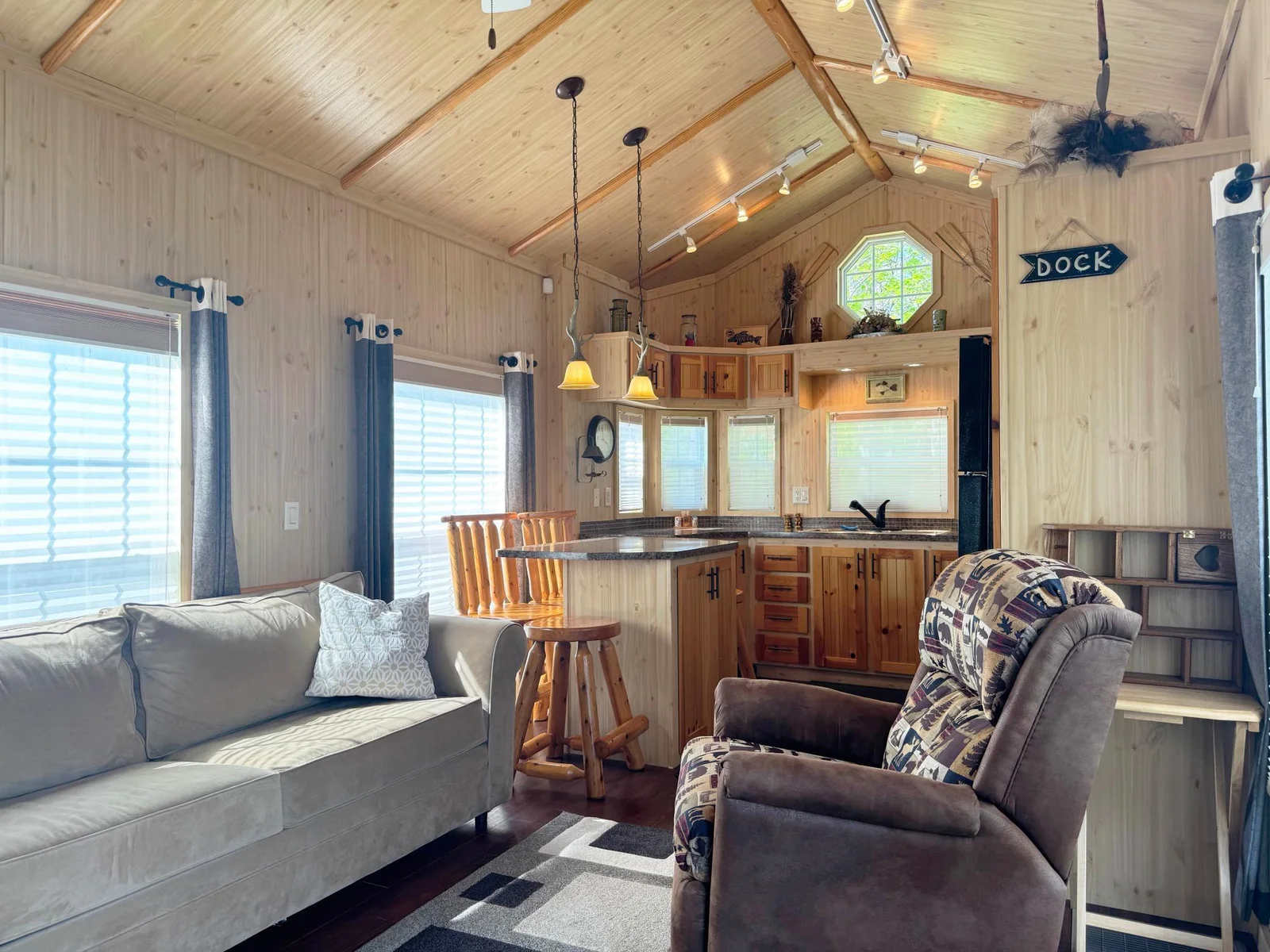 Living room view highlighting the vaulted tongue & groove ceiling that provides a spacious open feel with windows views overlooking both the lake and the "nature/pond" area in the back yard!