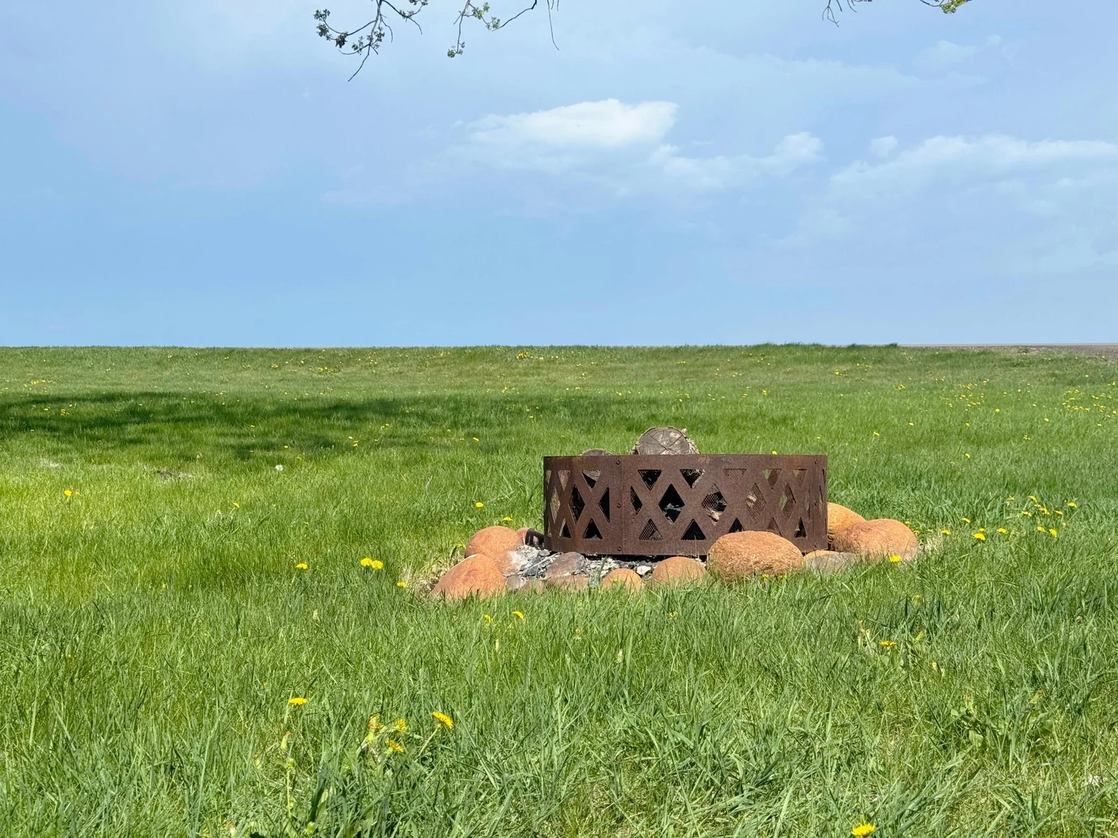 A closer look at the firepit ring in the front yard with the lake just beyond on other side of highway.