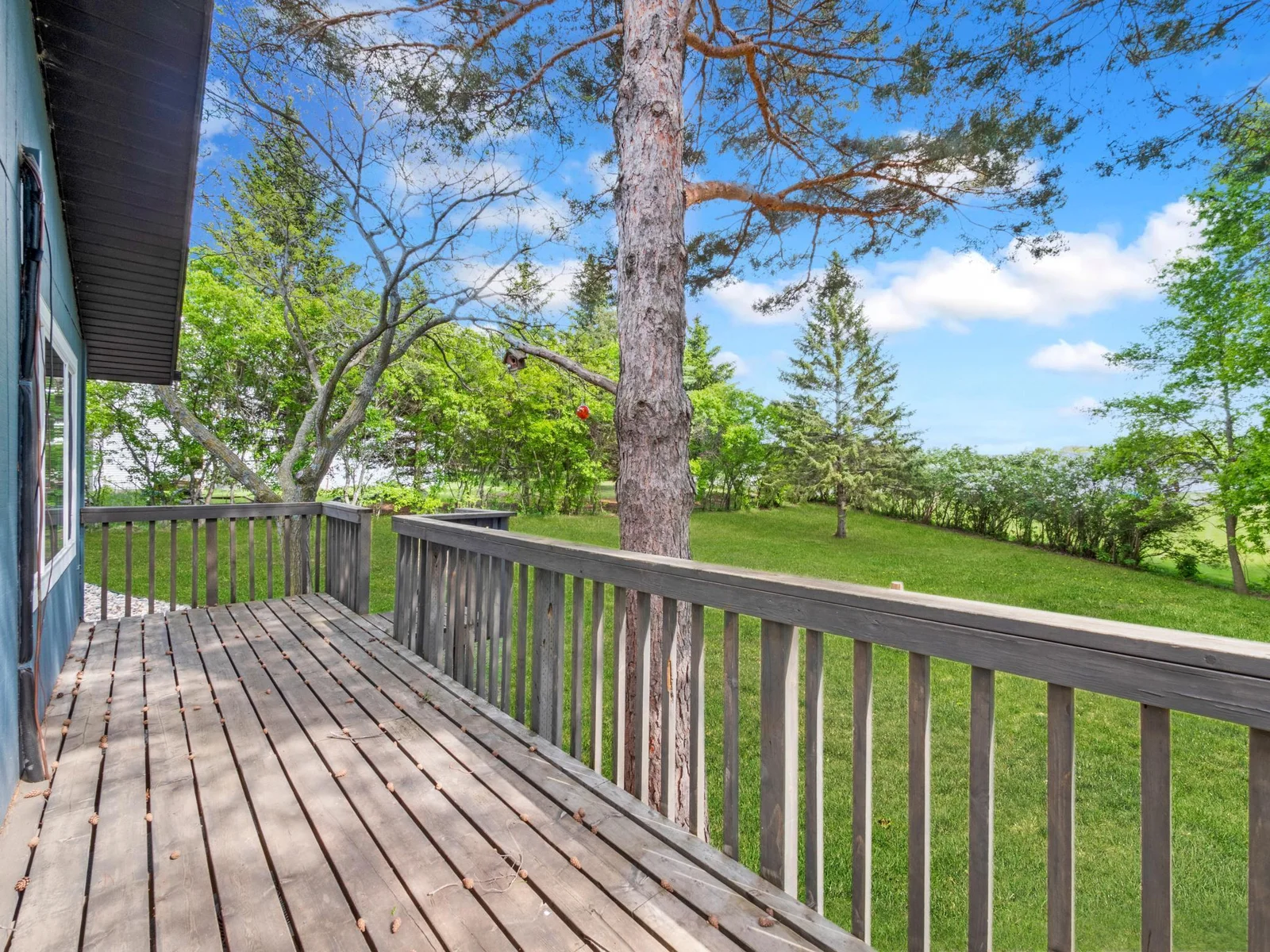 The wooden deck overlooks the spacious backyard and offers steps for easy access.