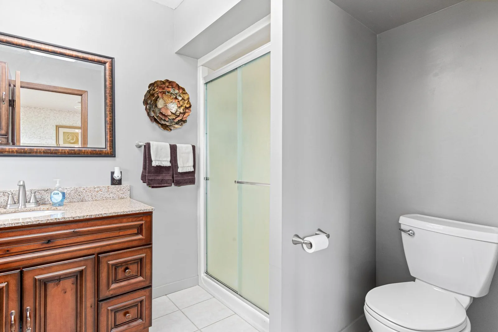 The primary bathroom features neutral tile, updated lighting, and large vanity with granite top and undermount sink.