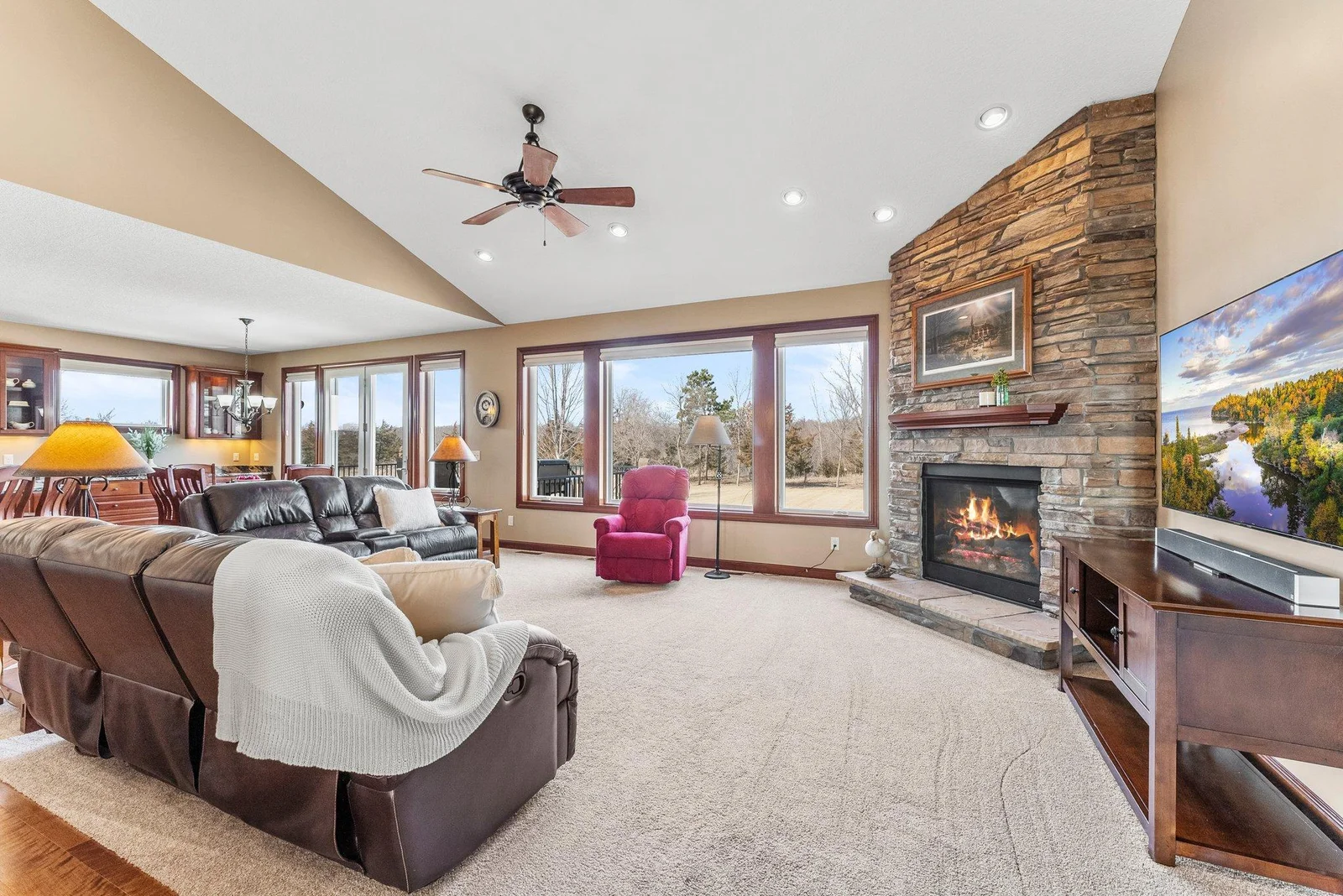 The living room is anchored by an impressive floor-to-ceiling gas fireplace, while an abundance of windows allows natural light to flood the home and offers sweeping views of the backyard.