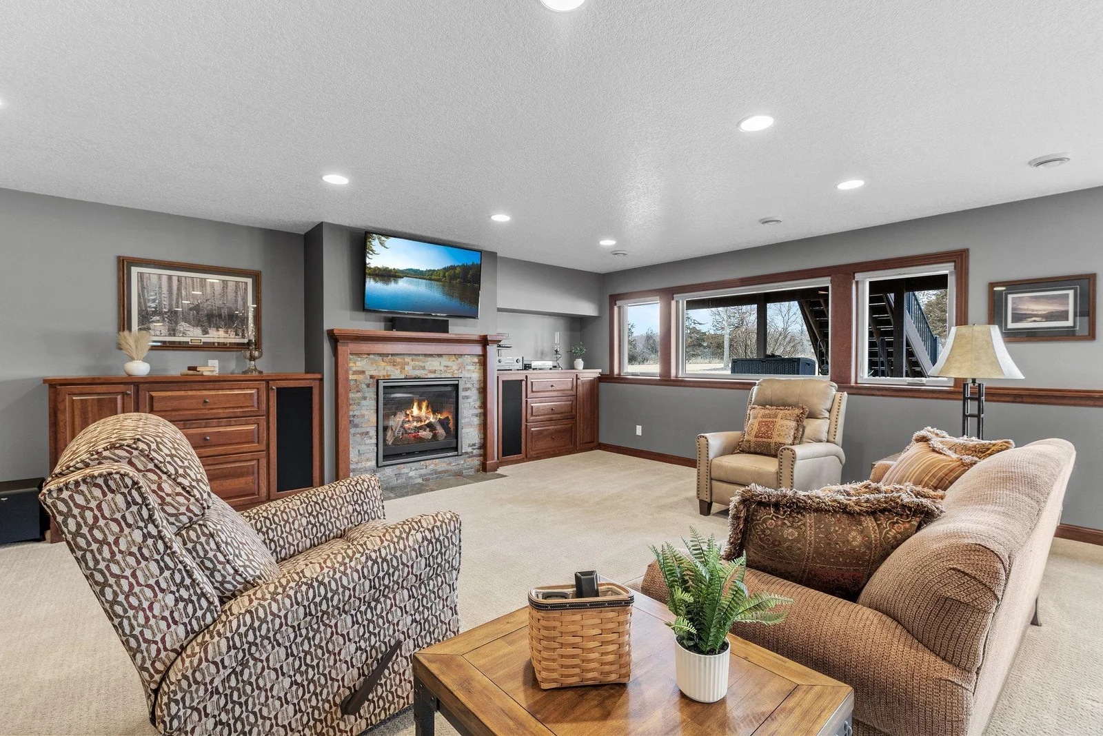 A wall of windows brings in abundant natural light, while built-in cabinetry provides stylish storage. The stone-surround gas fireplace creates a welcoming ambiance.