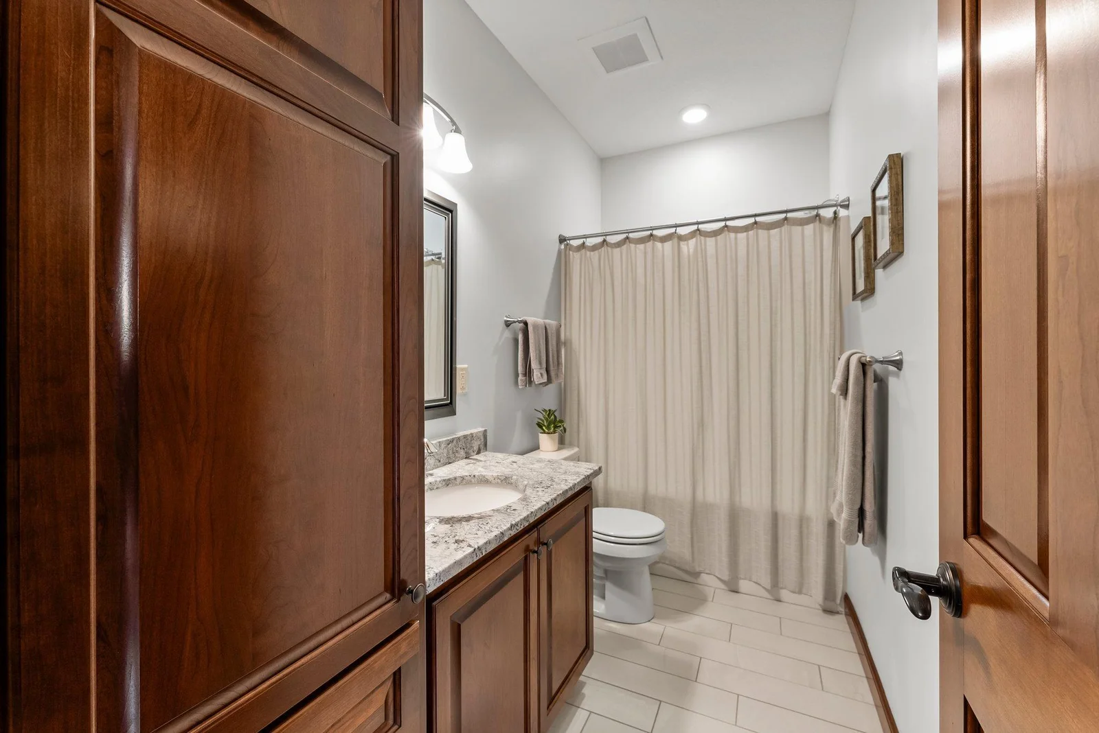A full bathroom with a granite vanity and linen cabinet serves these rooms, offering both style and functionality.