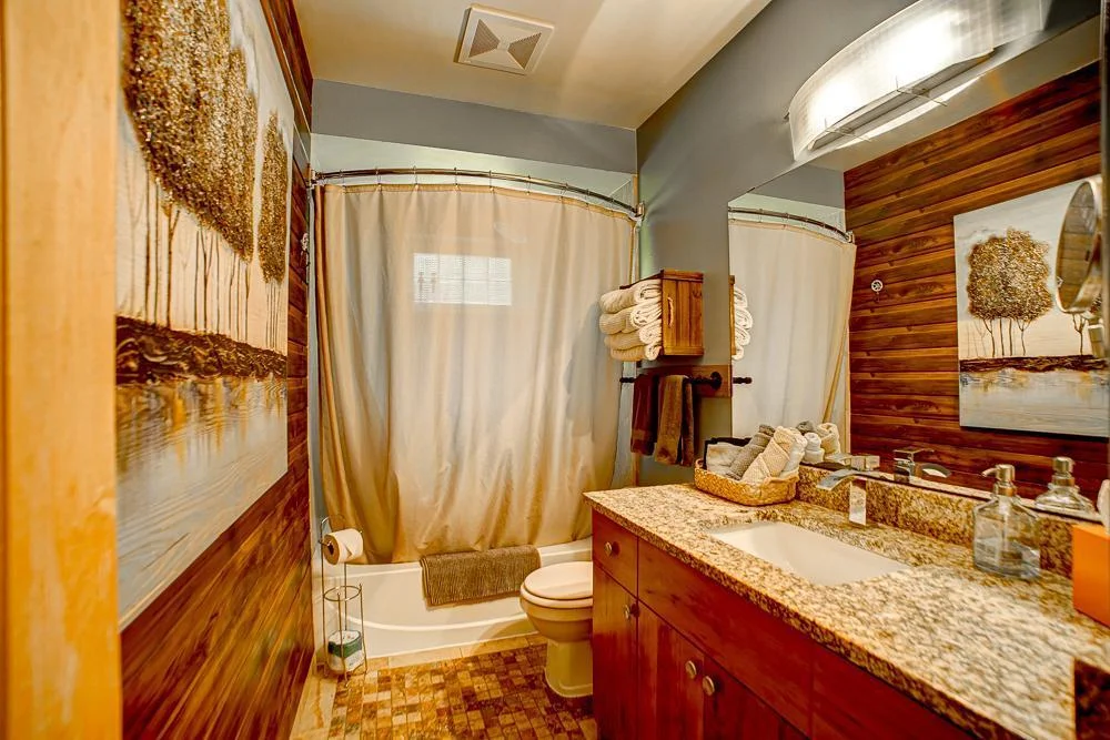 Main level full bathroom with stone countertop.