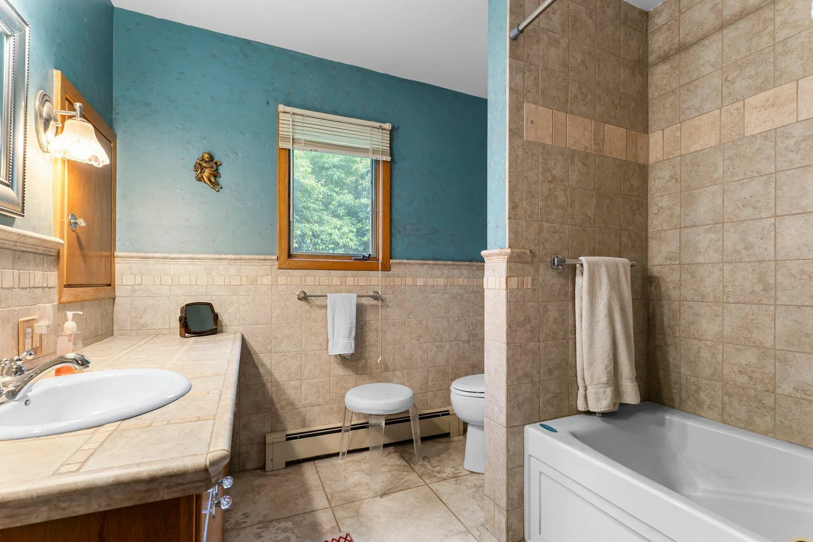 A full bathroom serves this level, complete with tiled floors, a large single vanity with tiled counters, and a jetted tub/shower combo. A nearby hall closet offers extra storage for linens and more.