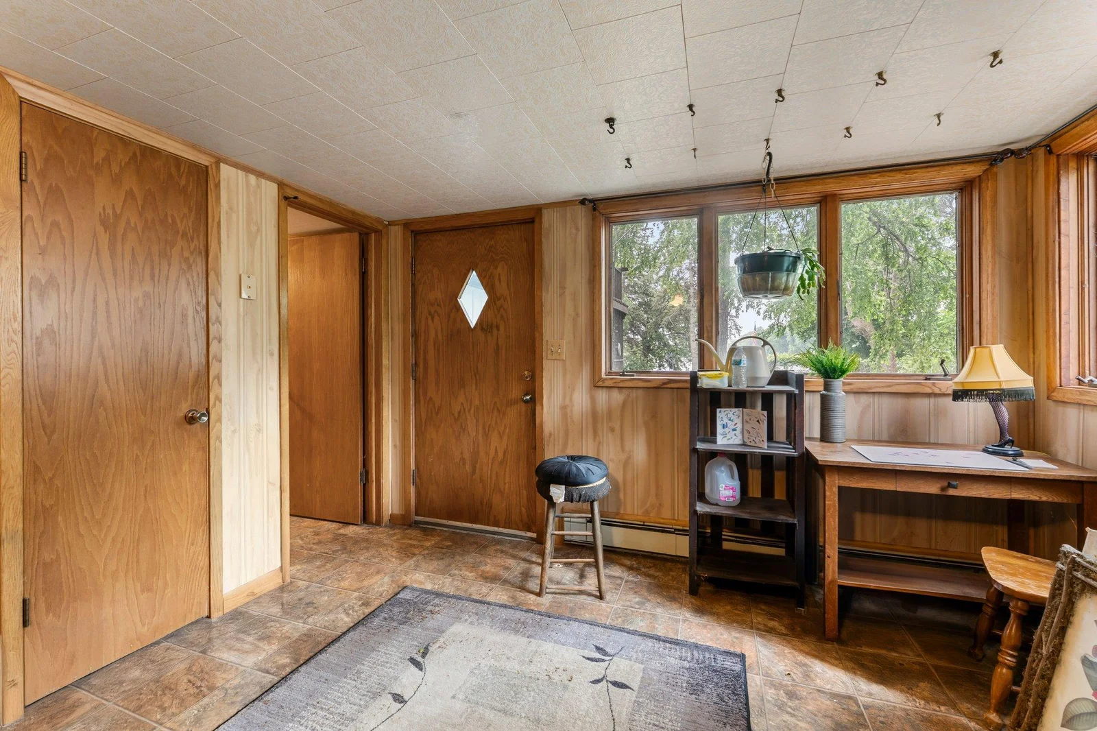 The lower level extends your living space with a generous family room featuring warm wood walls, durable tile flooring, a second wood-burning fireplace, and a ceiling fan. Walkout access to the backyard enhances the versatility of this area.