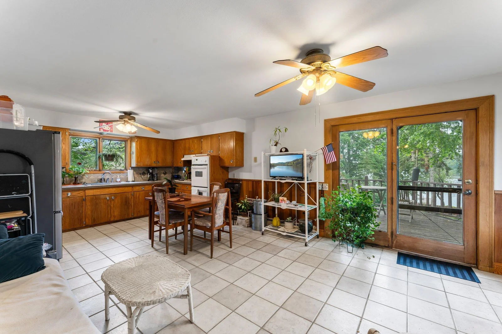 Just off the kitchen, the dining area boasts cohesive tile flooring, a ceiling fan for year-round comfort, and a built-in glass-front china cabinet. Access to the deck allows for easy indoor-outdoor entertaining.