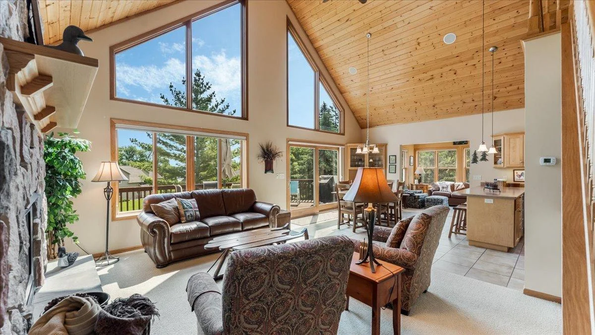 4132 Omaha Lane NW, Alexandria, MN 56308 Great room with floor to ceiling windows, and a beautiful stone fireplace.  This is a year-round retreat! Notice the wood vaulted ceiling!