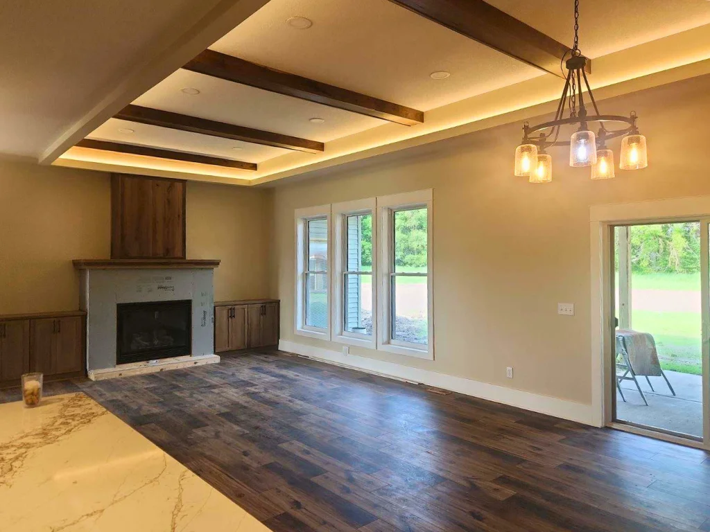 Your great room features soaring 10’ and 11’ ceilings with ambient back lighting, a gas fireplace adorned with a Knotty Black Walnut hood and flanked with build in storage cabinets, and continuous LVP flooring throughout.