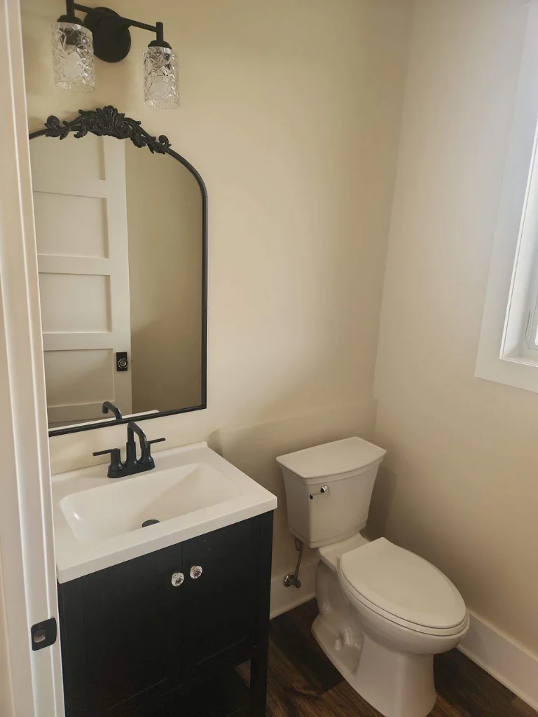 Convenient half bath on the main level featuring a beautiful black accent vanity, mirror, and light fixture.