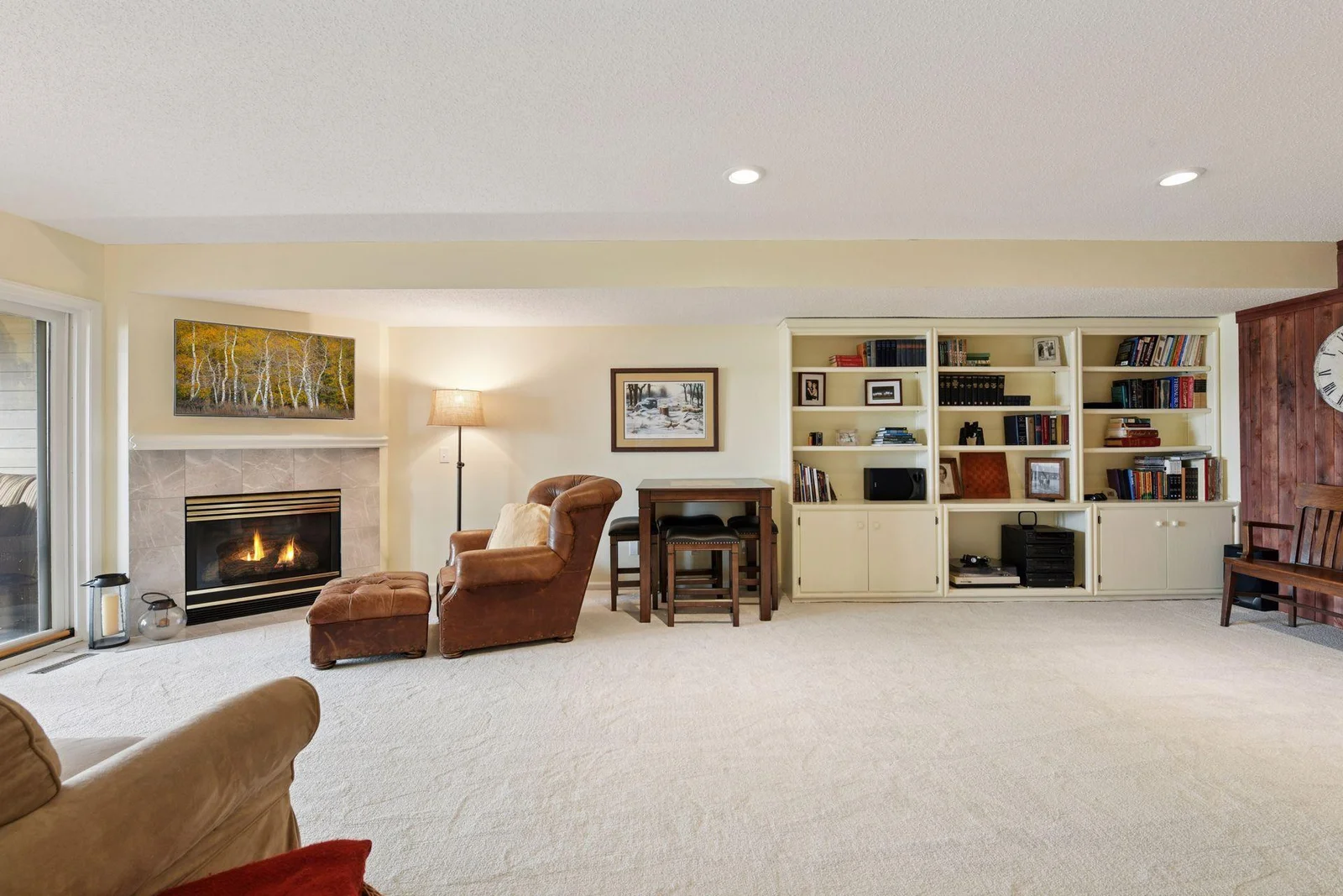 The open-concept lower level family room features built-in bookcases and a high-top table with chairs—perfect for playing cards, board games, or simply gathering with friends and family.