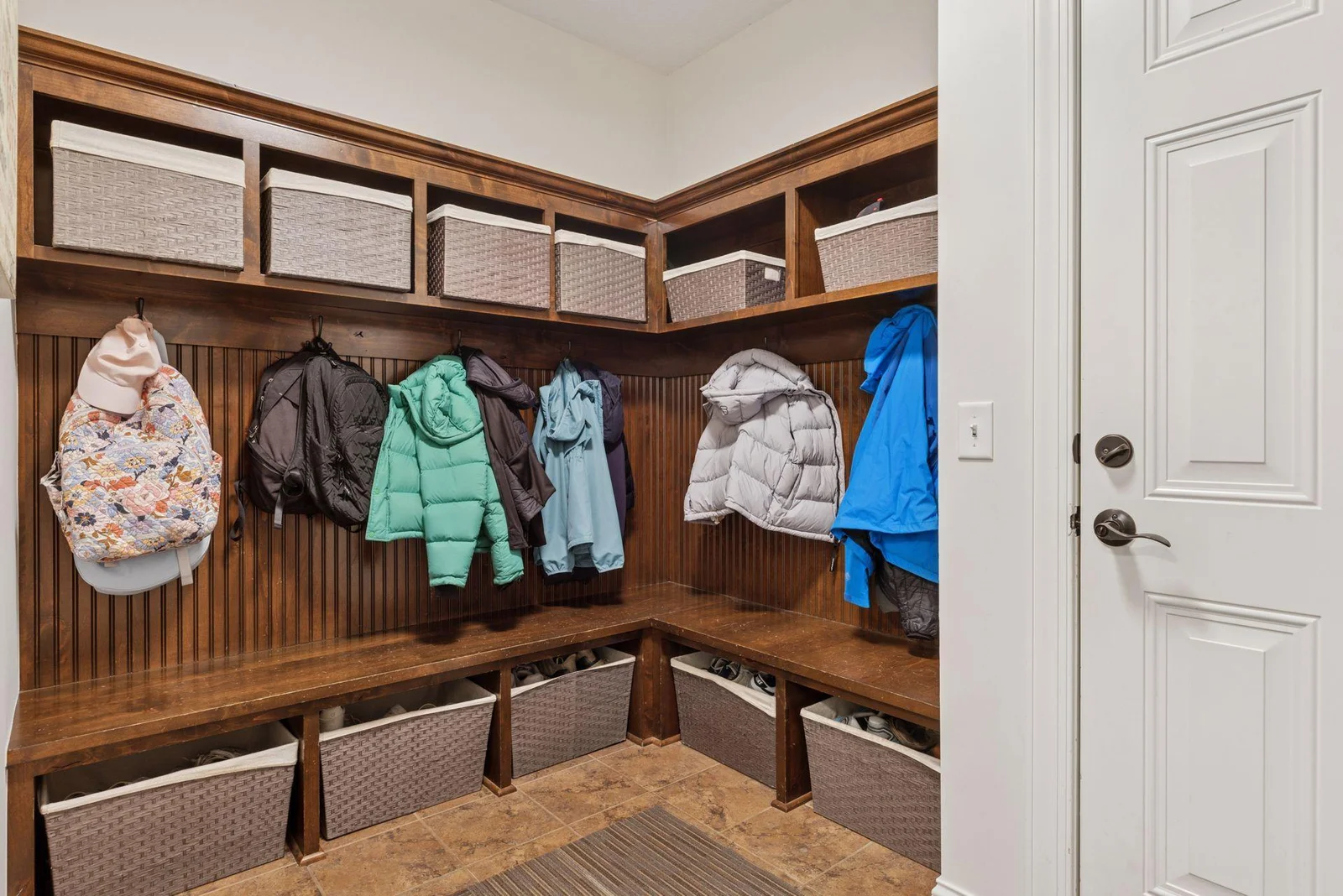 The spacious mudroom just off the garage features built-in benches, sturdy hooks, and open cubbies—perfect for keeping coats, shoes, and backpacks organized.