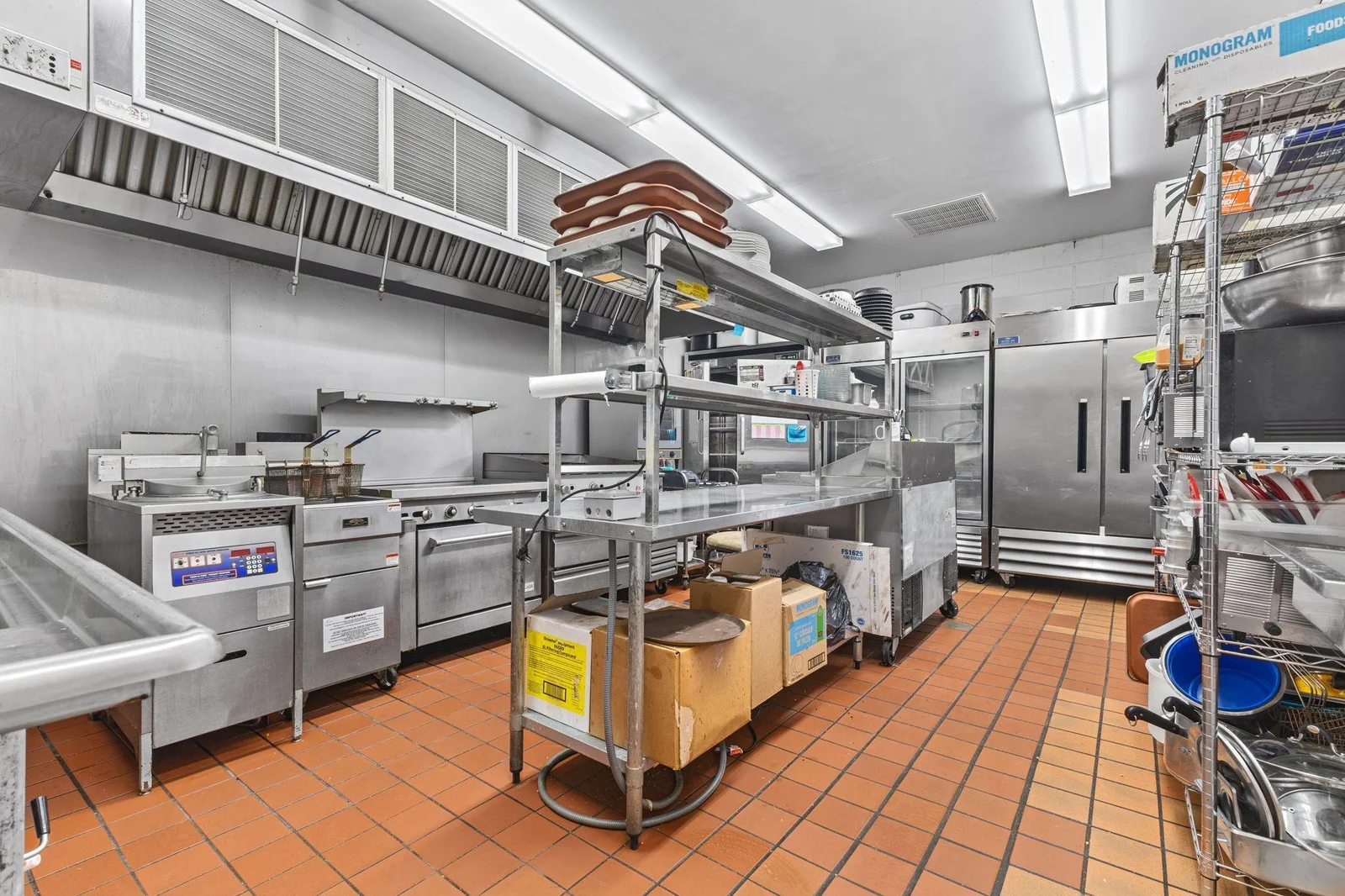 Commercial kitchen with grill, ovens, fryer, refrigerators, freezer, shelving & racks, warming and food prep area and so much more.