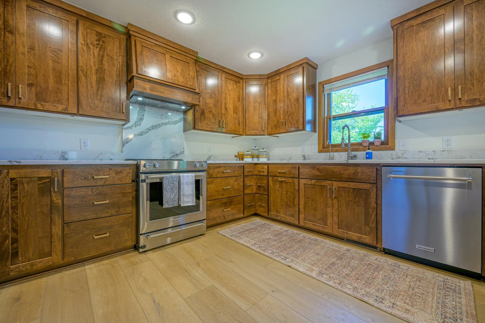 The kitchen features Schlangen's custom maple cabinets, quartz countertops, and S.S. Kitchen Aid appliances.