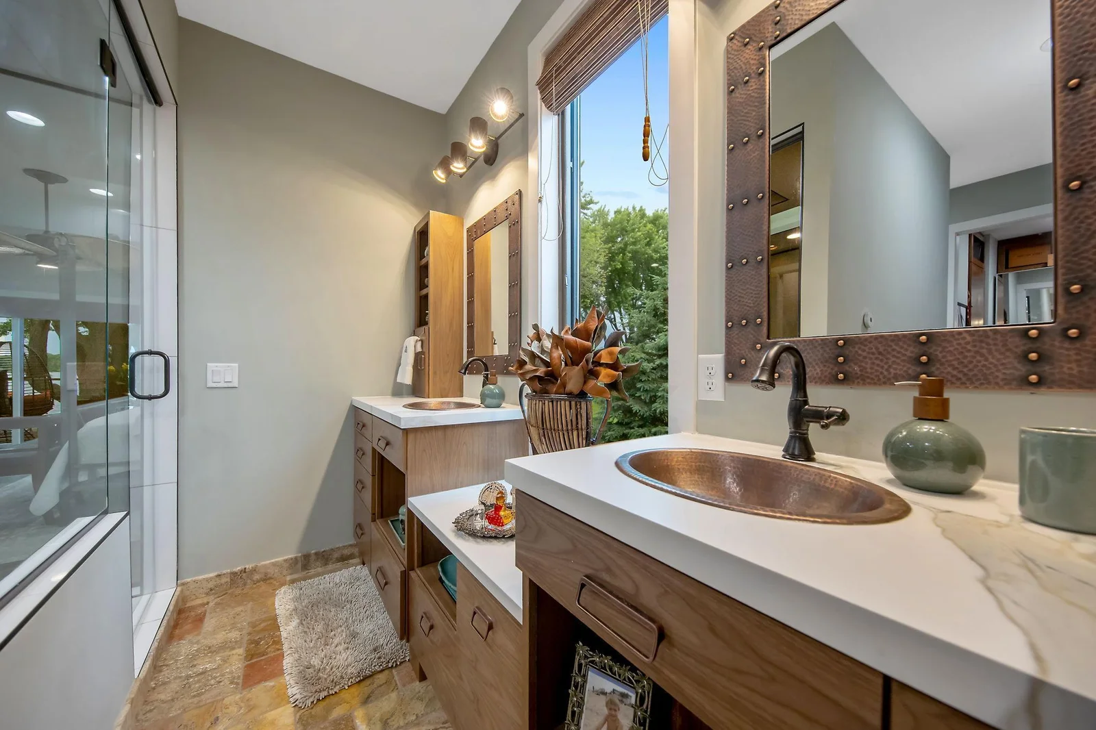 Owners bath with dual vanities and tons of storage. Copper sinks, natural light & lake views highlight this space.