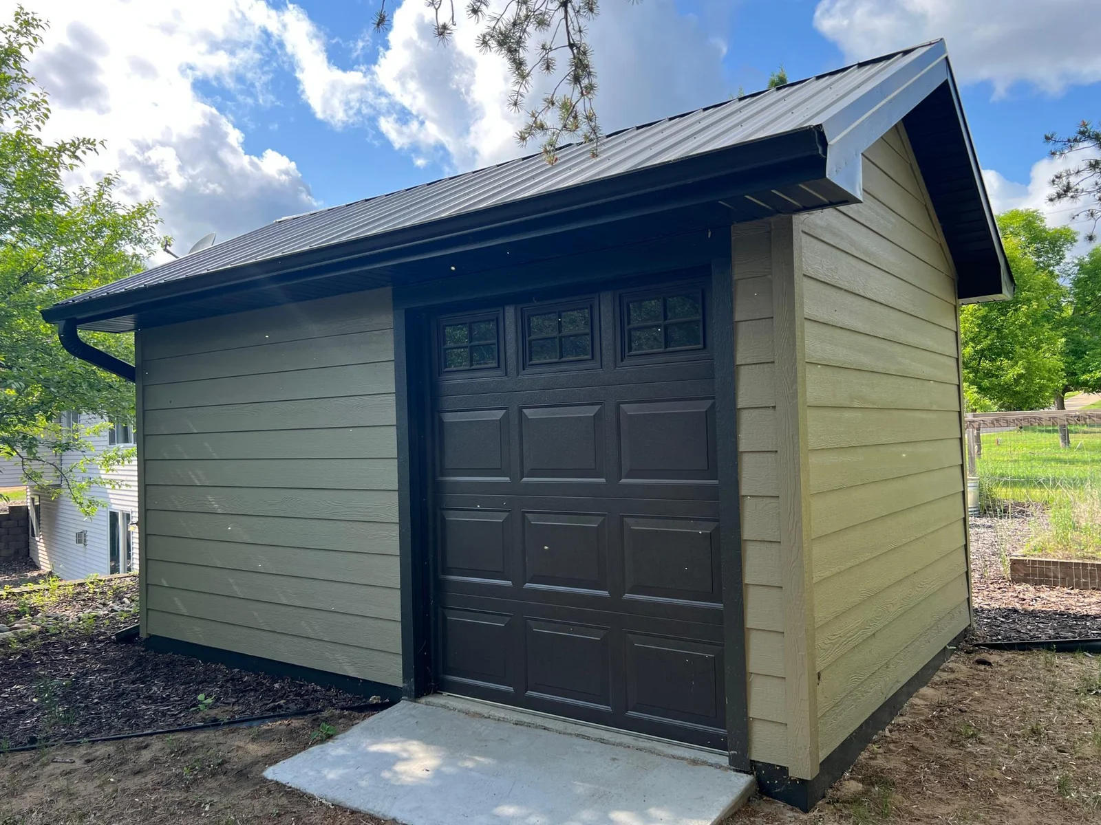 THE REAR EXTERIOR VIEW OF THE GARDEN SHED, WHICH HAS AN OVER HEAD DOOR, MAKING IT EASY TO PARK YOUR MOWER !
